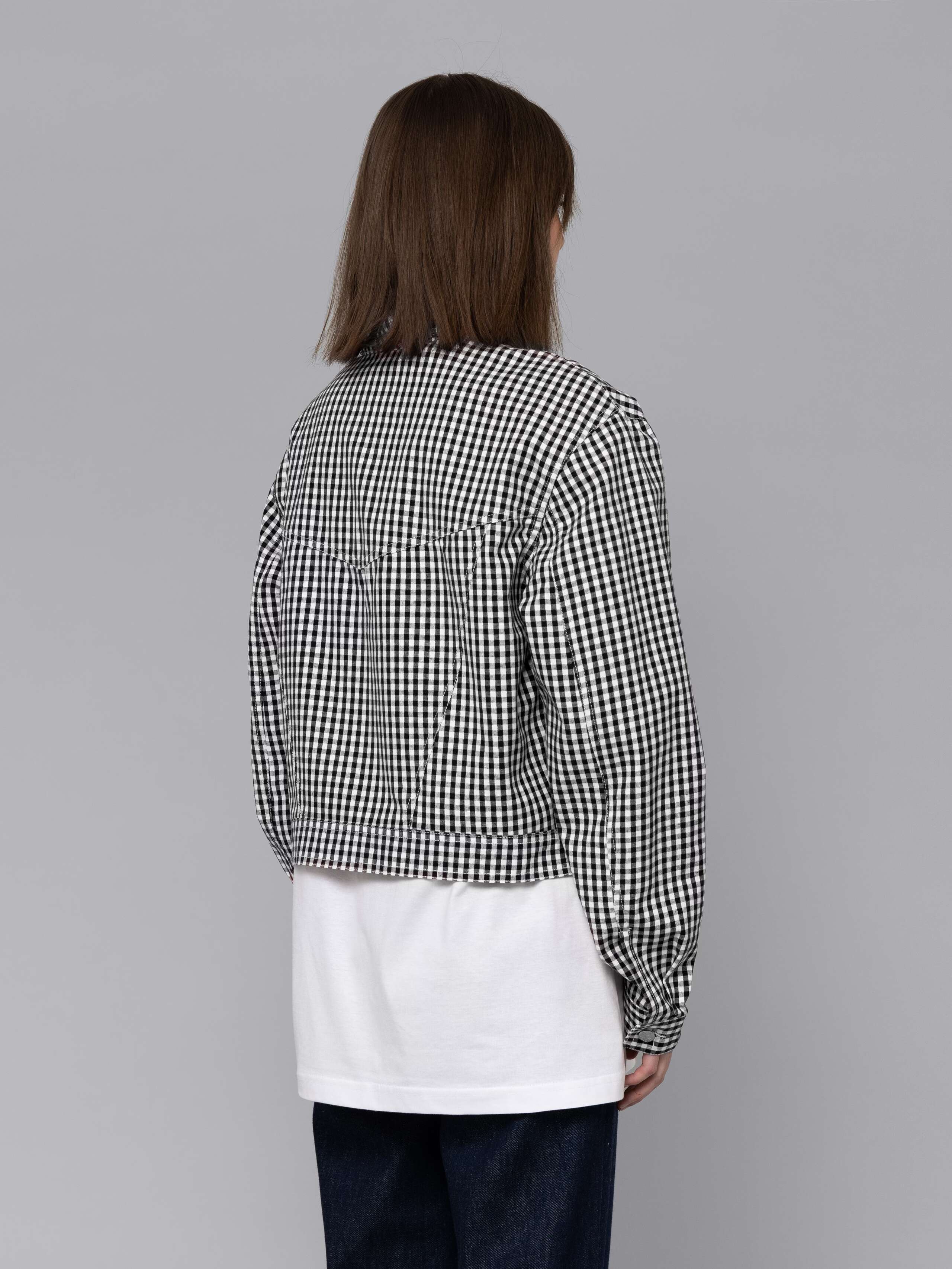 Female model is wearing a a boxy denim trucker jacket featuring a beautiful black vichy check pattern