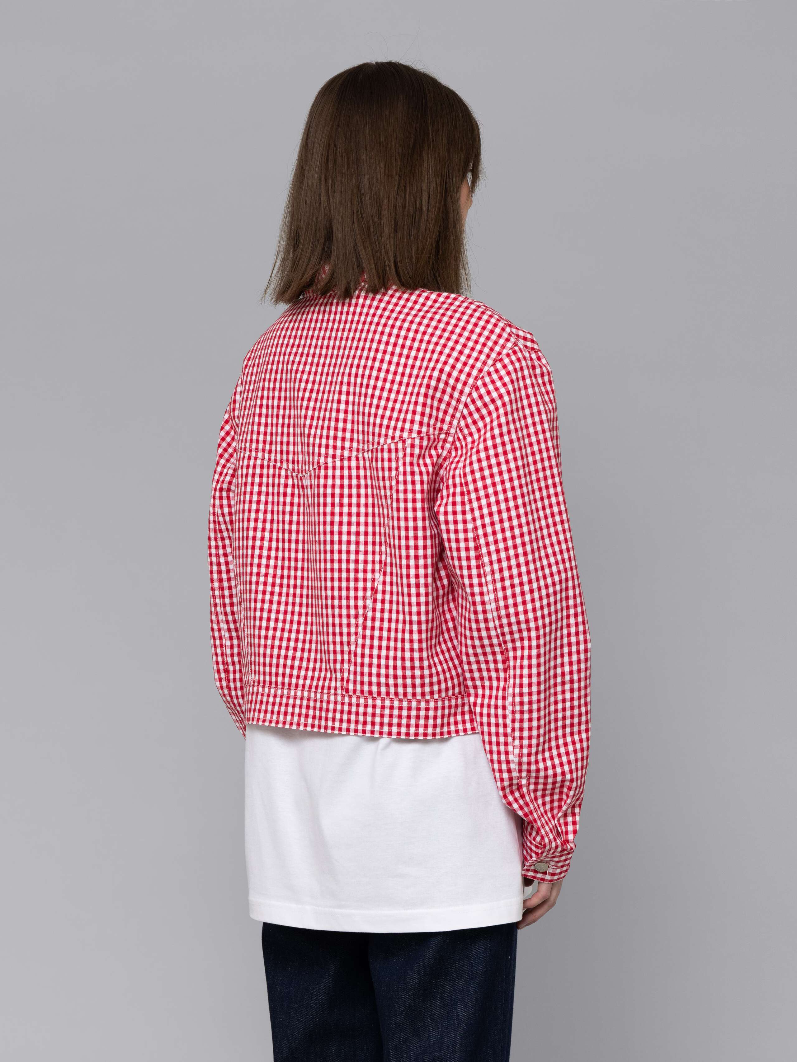 Female model is wearing a a boxy denim trucker jacket featuring a beautiful red vichy check pattern