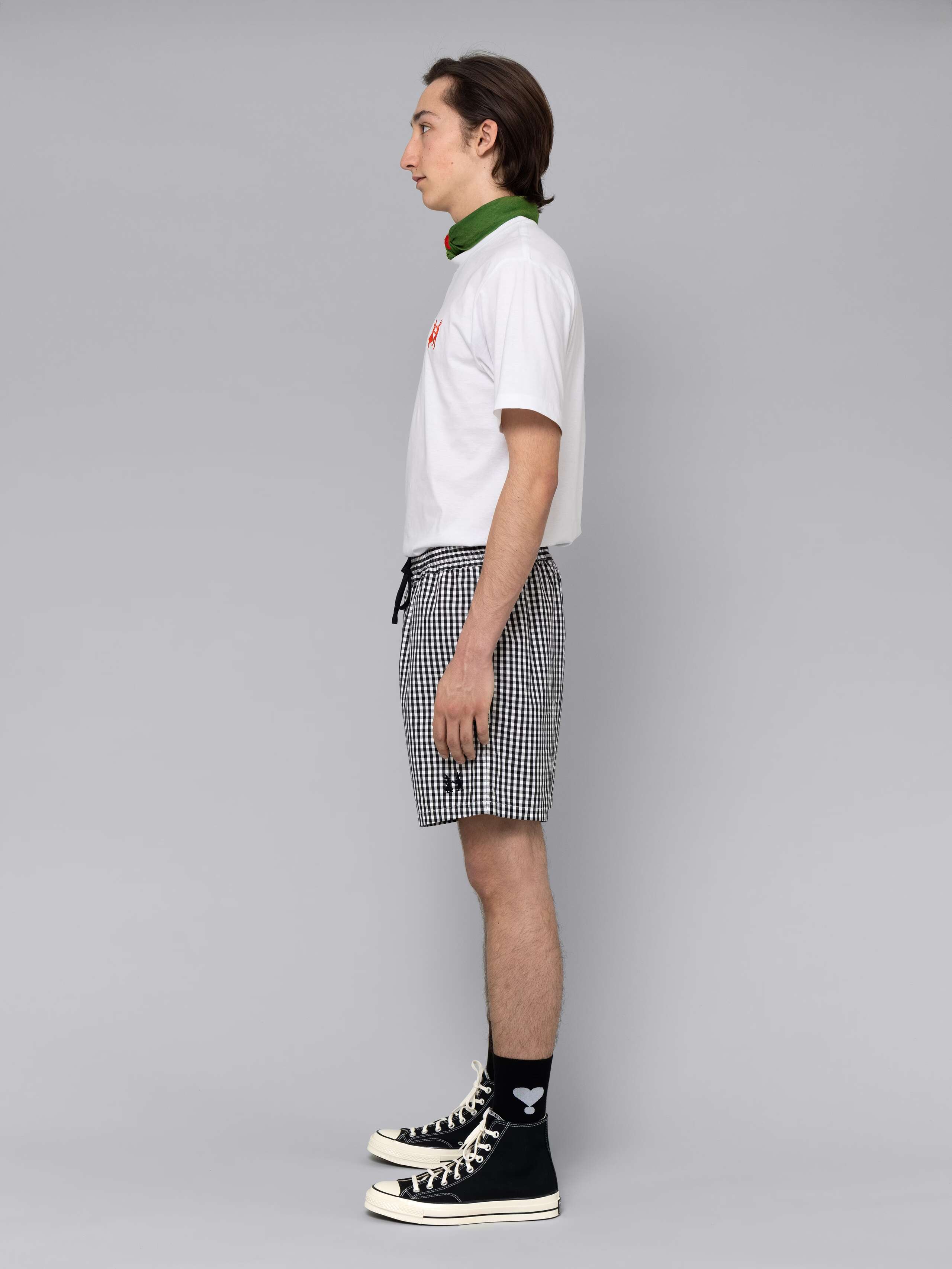 Male model is wearing a summery combination of a cotton short featuring a black vichy check pattern and a white t-shirt