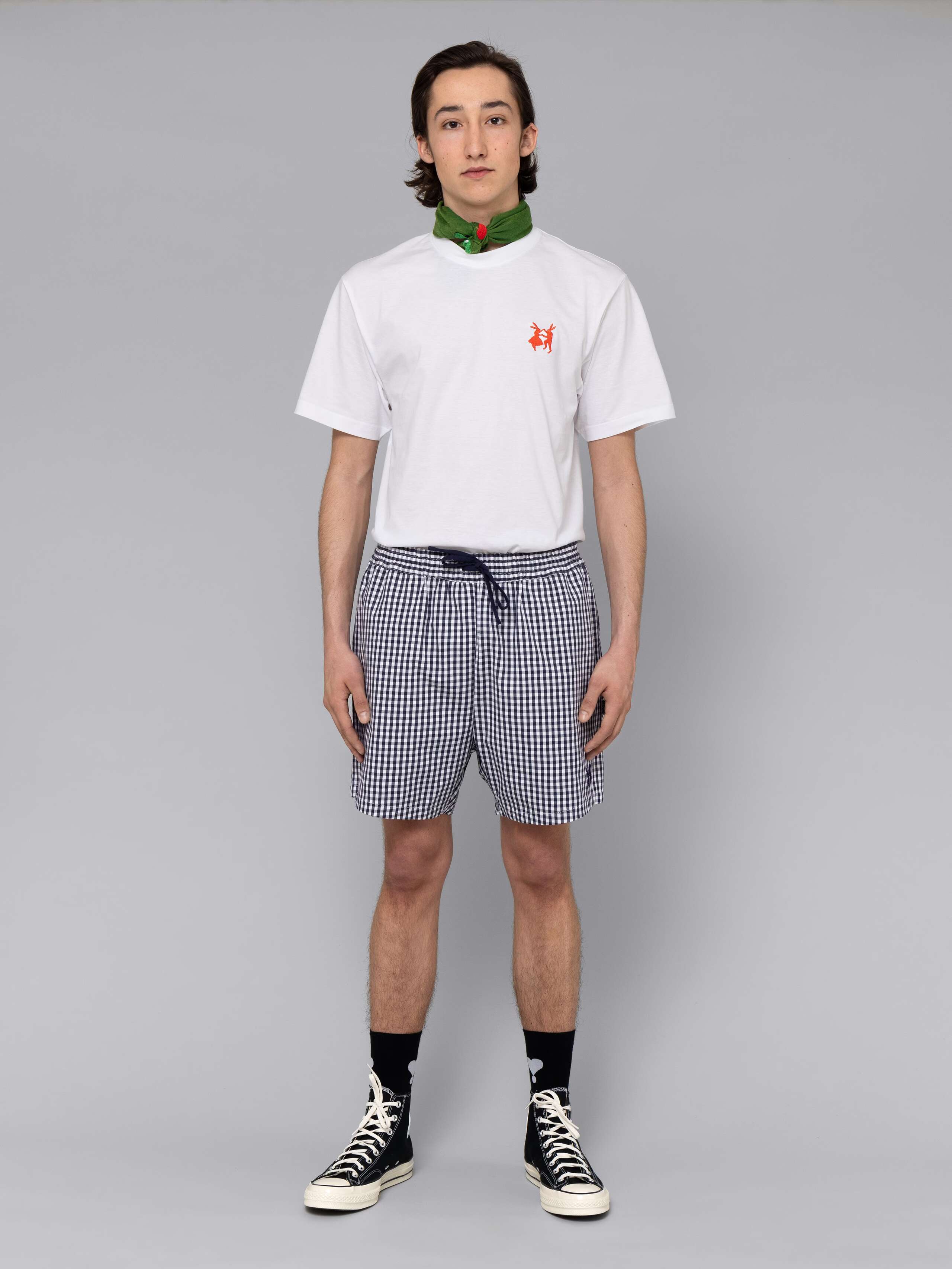 Male model is wearing a summery combination of a cotton short featuring a navy vichy check pattern and a white t-shirt