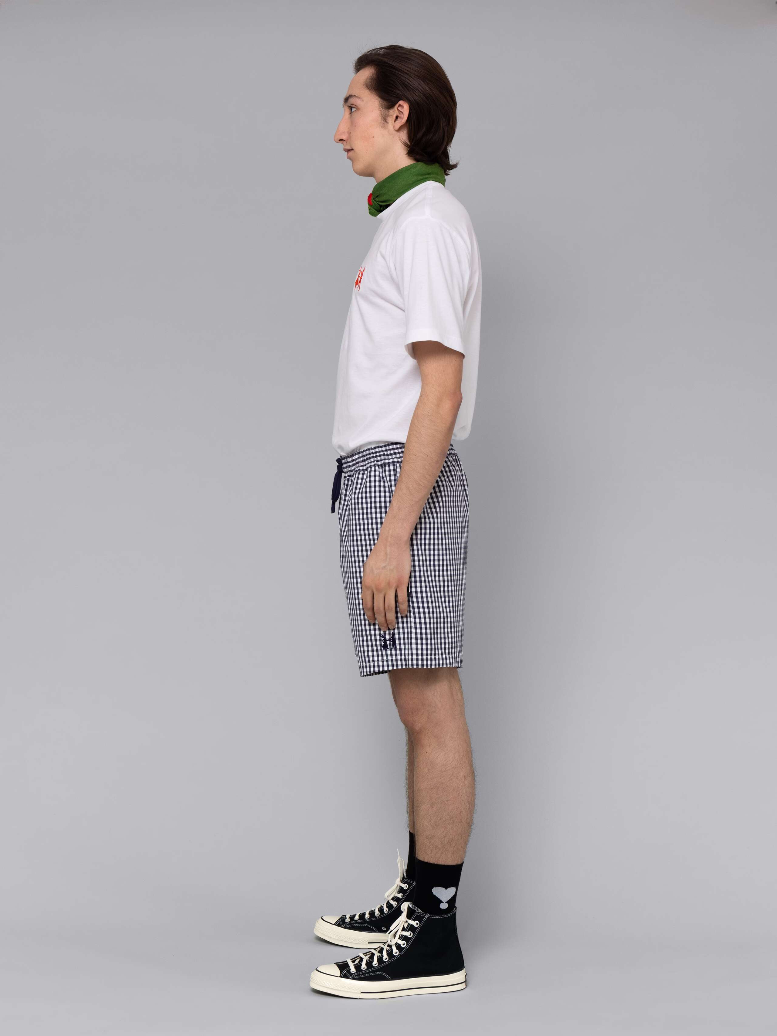 Male model is wearing a summery combination of a cotton short featuring a navy vichy check pattern and a white t-shirt