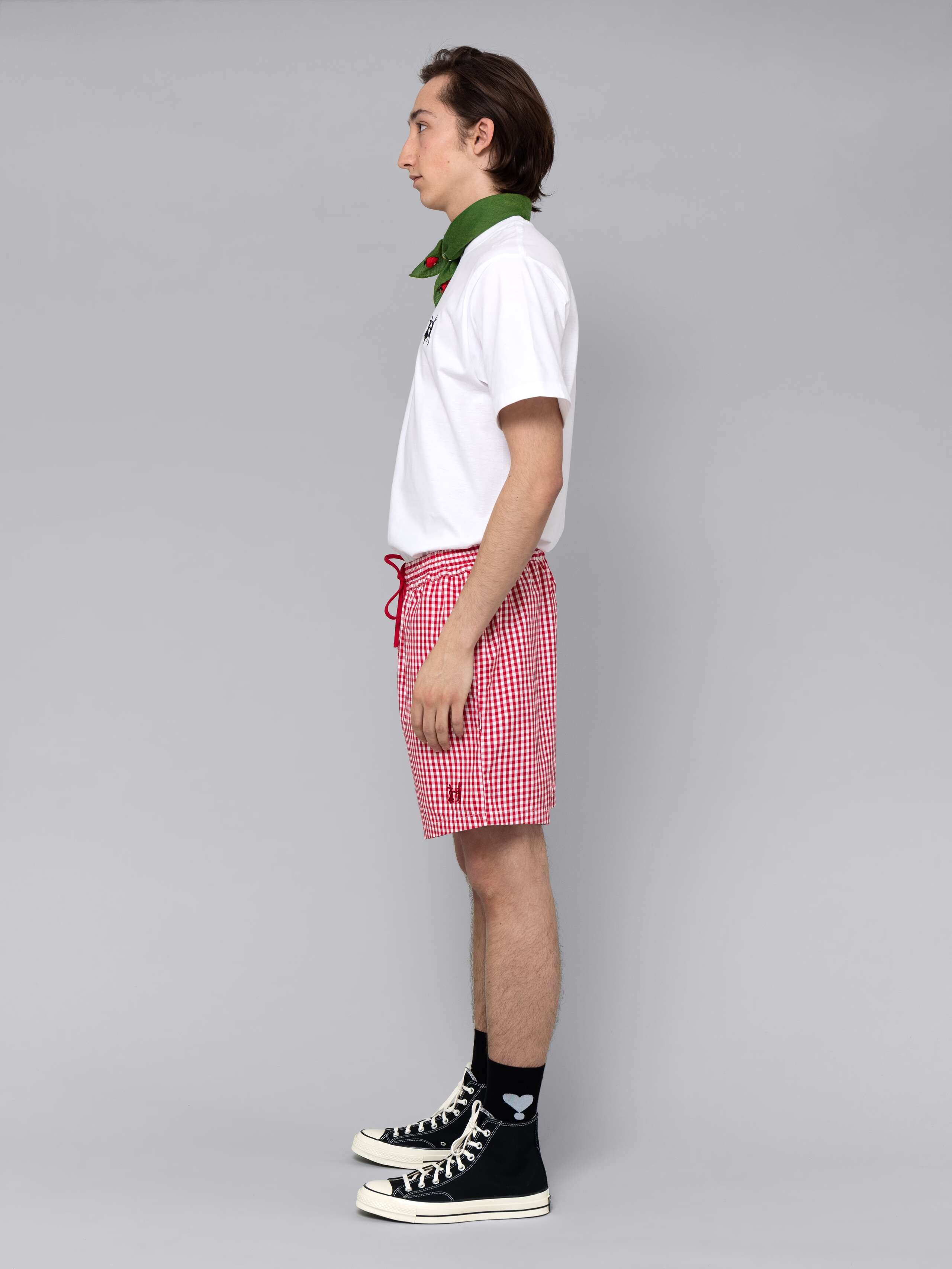 Male model is wearing a summery combination of a cotton short featuring a red vichy check pattern and a white t-shirt