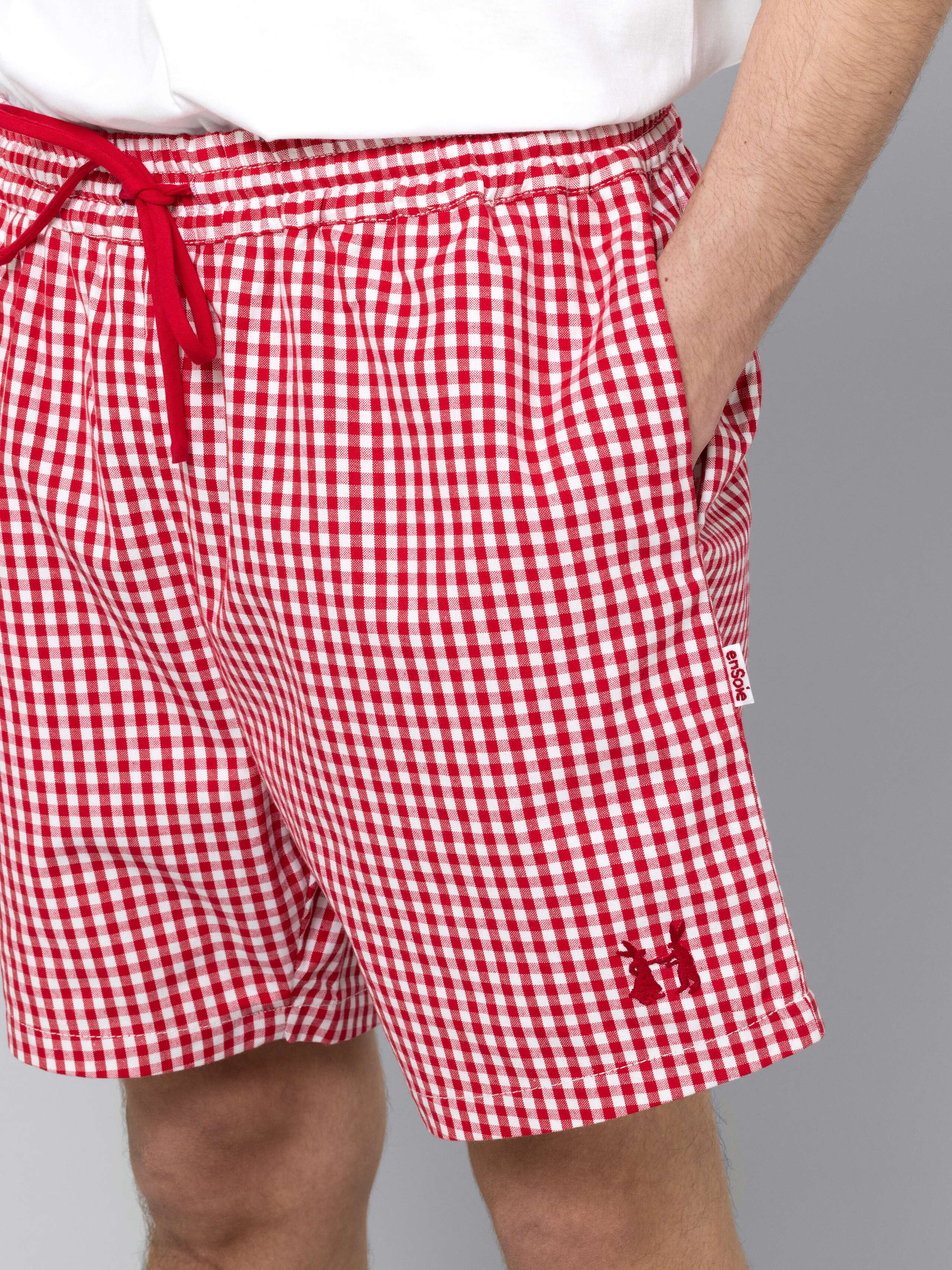 Male model is wearing a summery combination of a cotton short featuring a red vichy check pattern and a white t-shirt