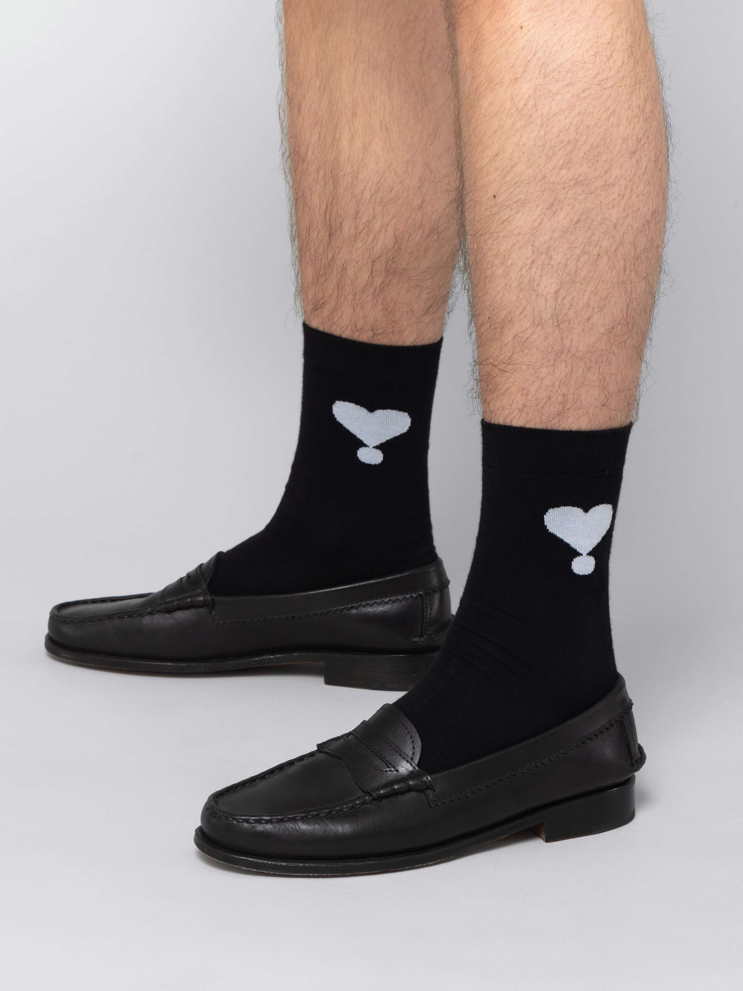Mal model is wearing black socks with white hearts in black leather shoes