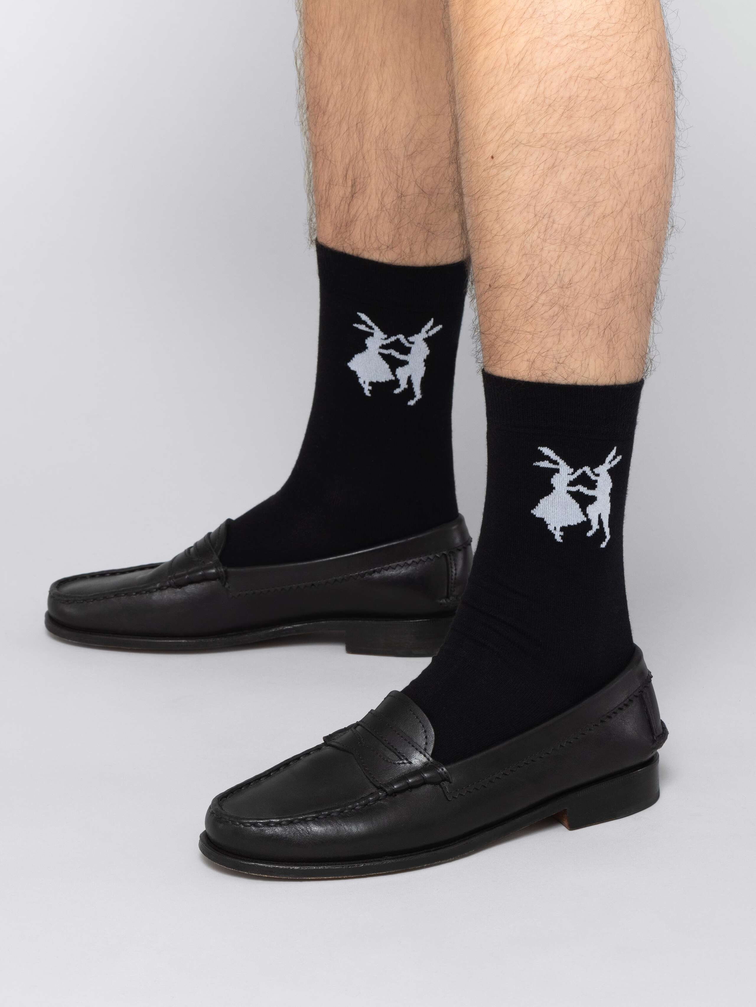 Mal model is wearing black socks with white rabbits in black leather shoes