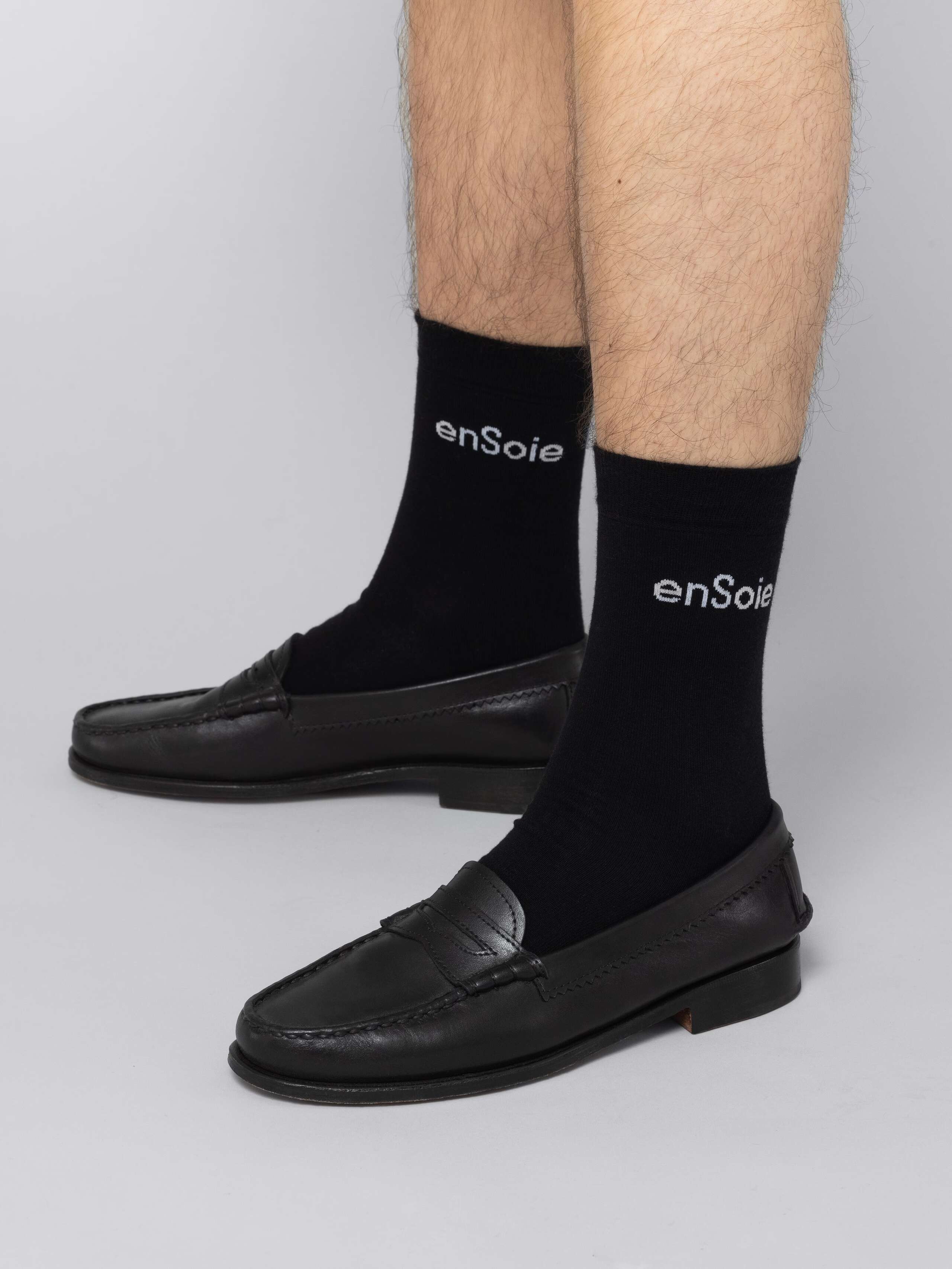 Mal model is wearing black socks with white enSoie logo in black leather shoes