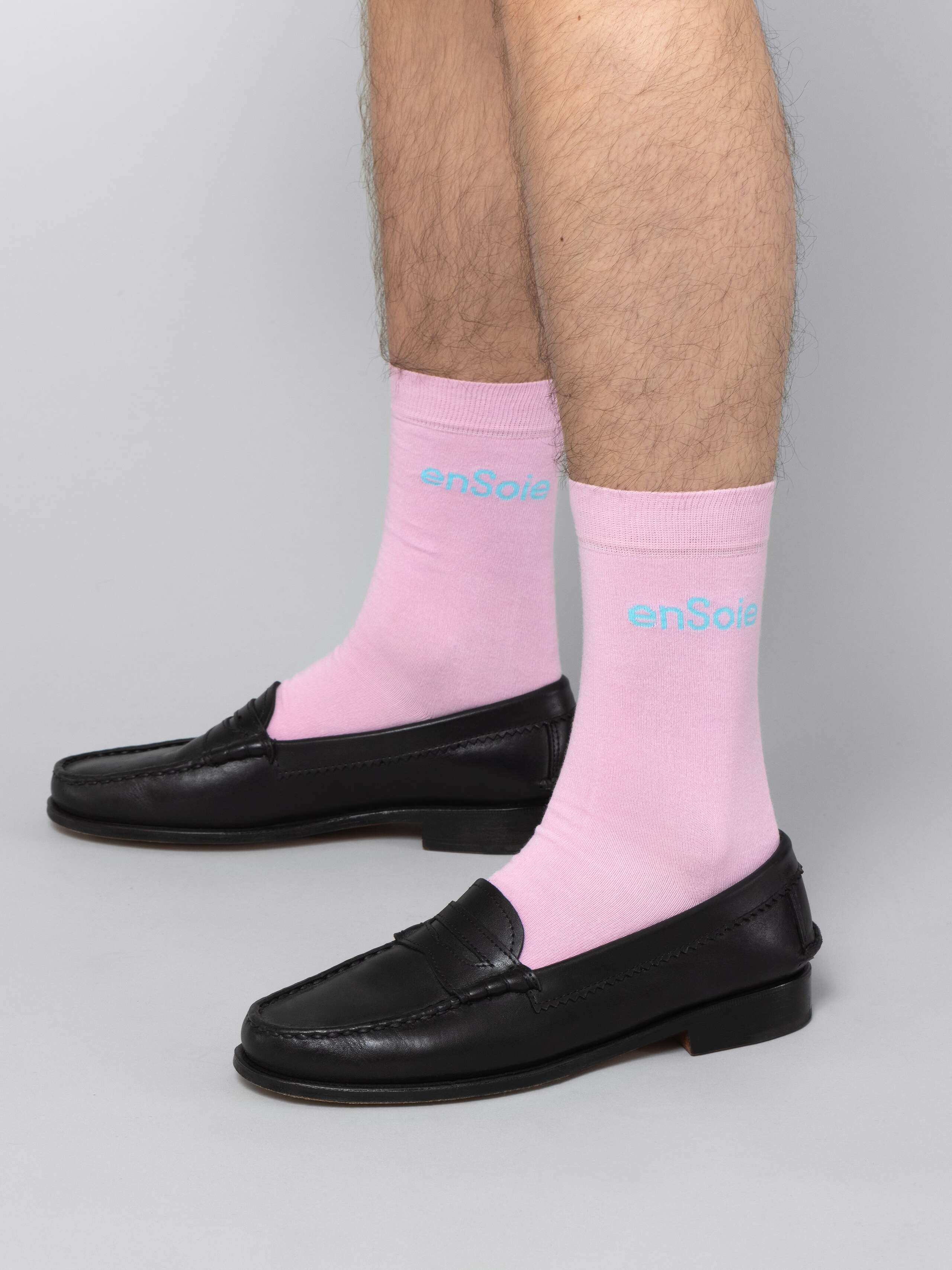 Mal model is wearing pink socks with blue enSoie logo in black leather shoes
