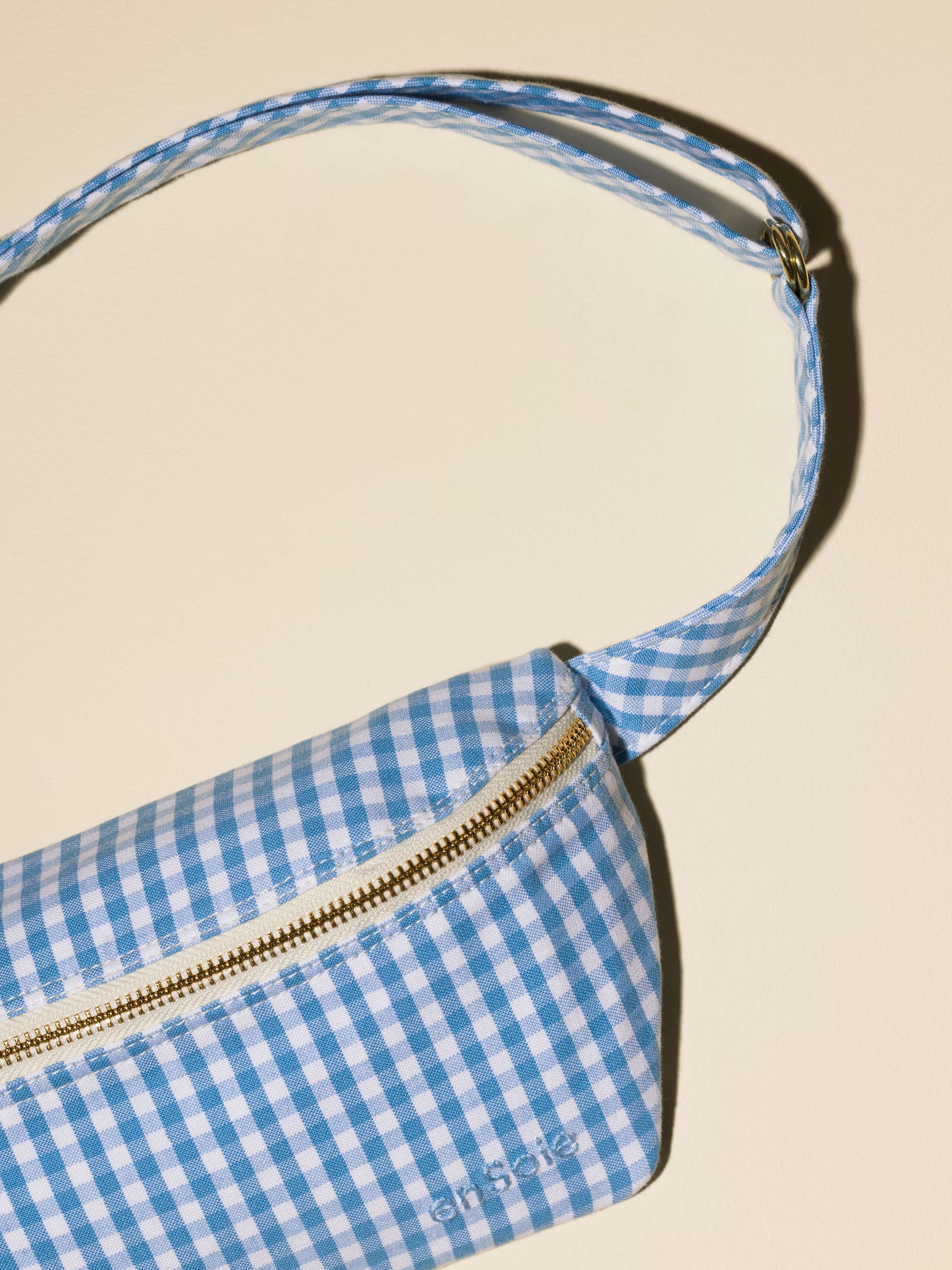 Picture of a cute cotton hip bag featuring a light blue vichy check pattern and a striped pattern
