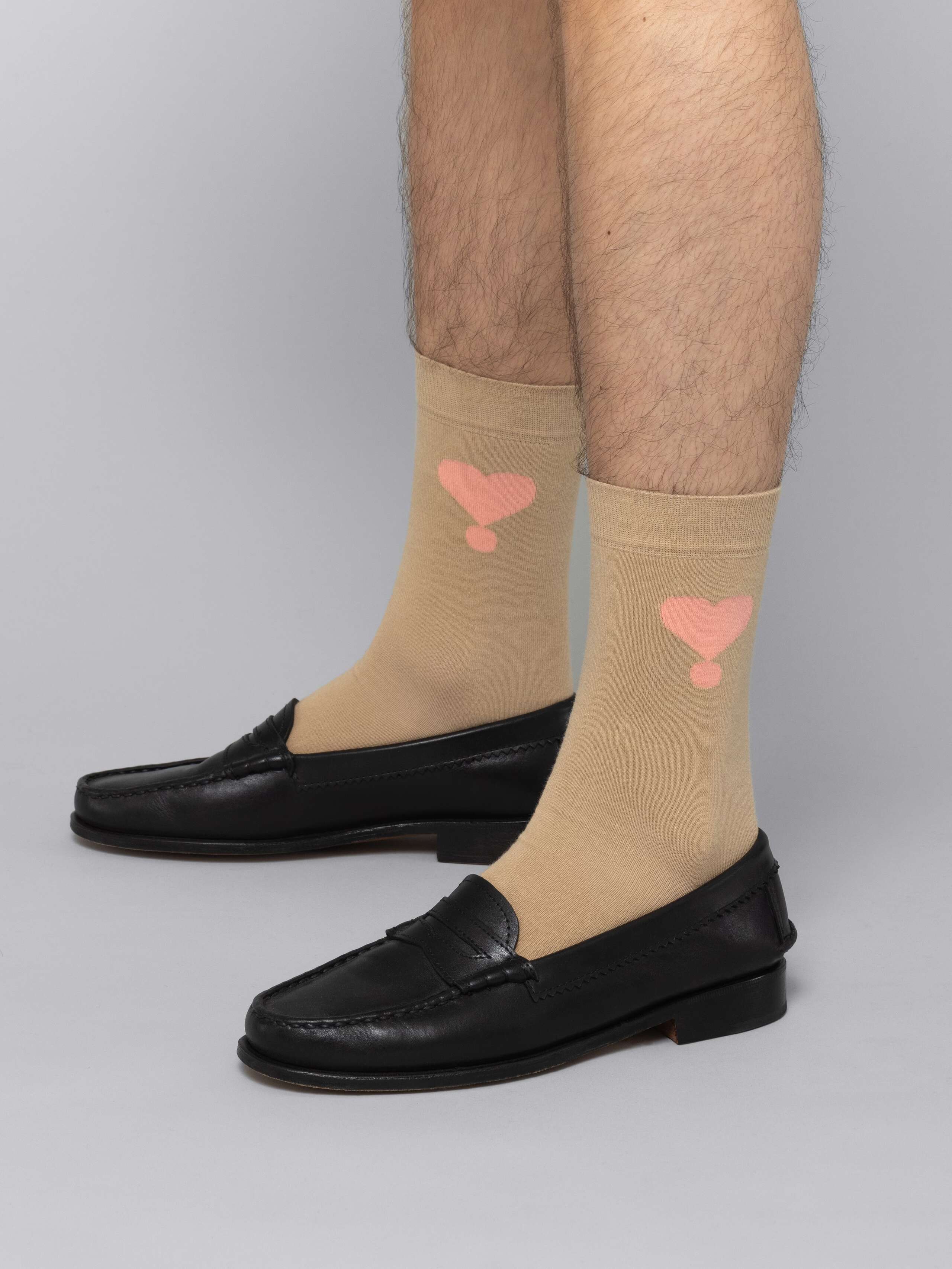 Male model is wearing beige socks with pink enSoie logo in black leather shoes