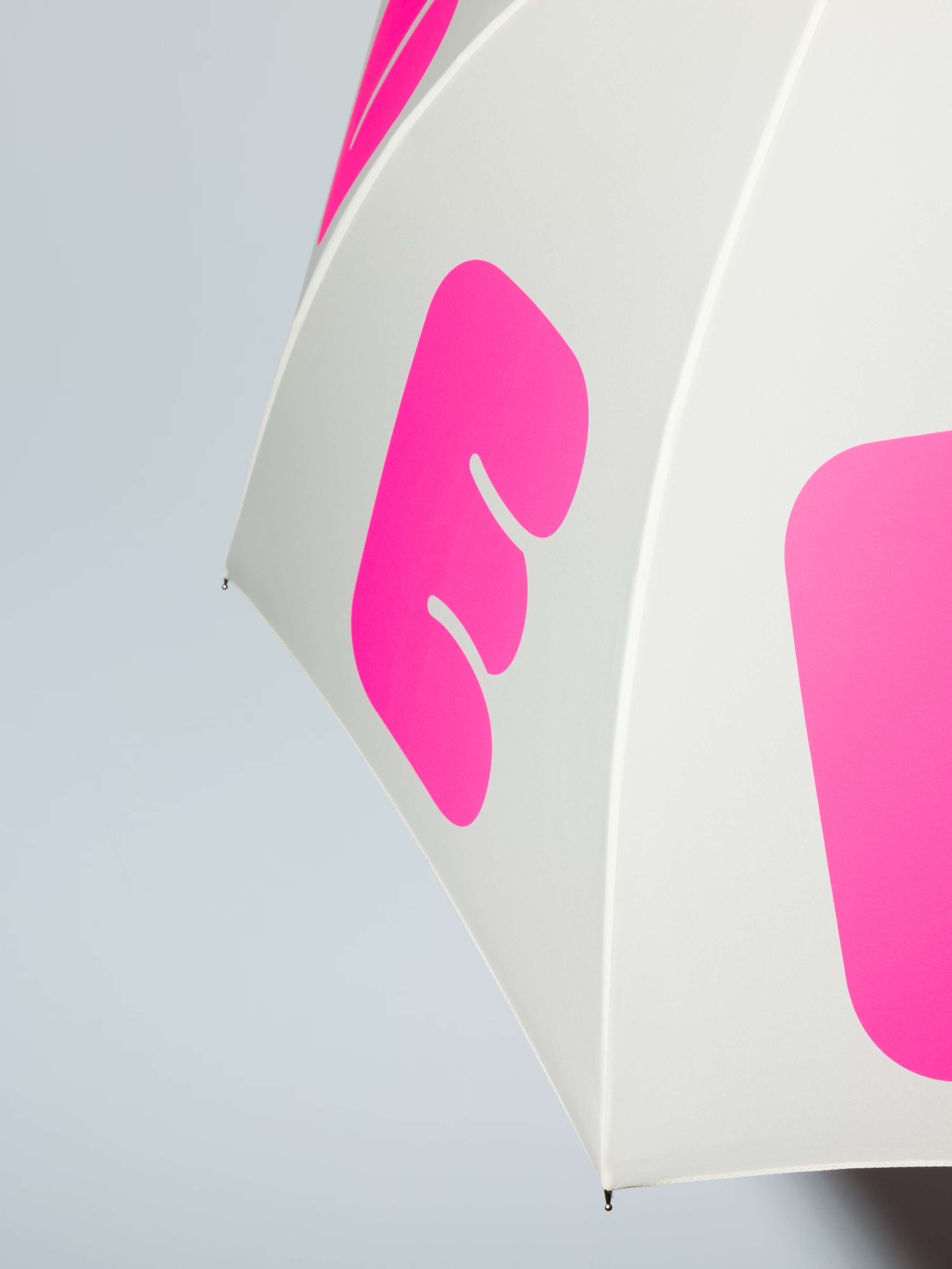 Picture of a detail of a white umbrella with the motto "love rules forever" in pink