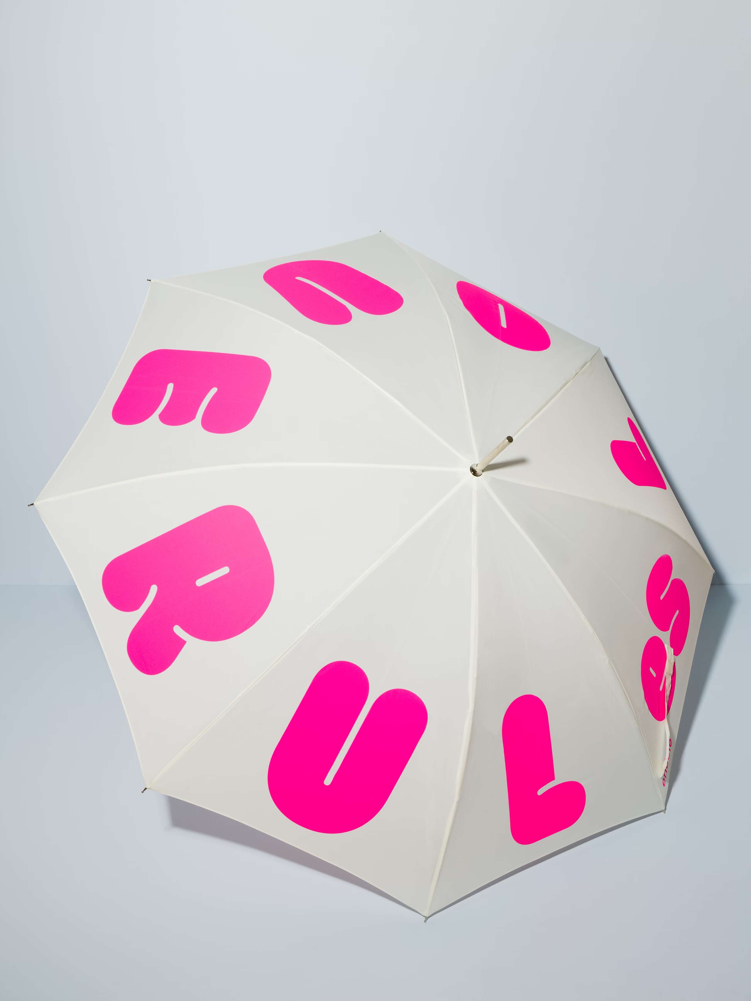 Picture of a white umbrella featuring a motto print "love rules forever" in pink