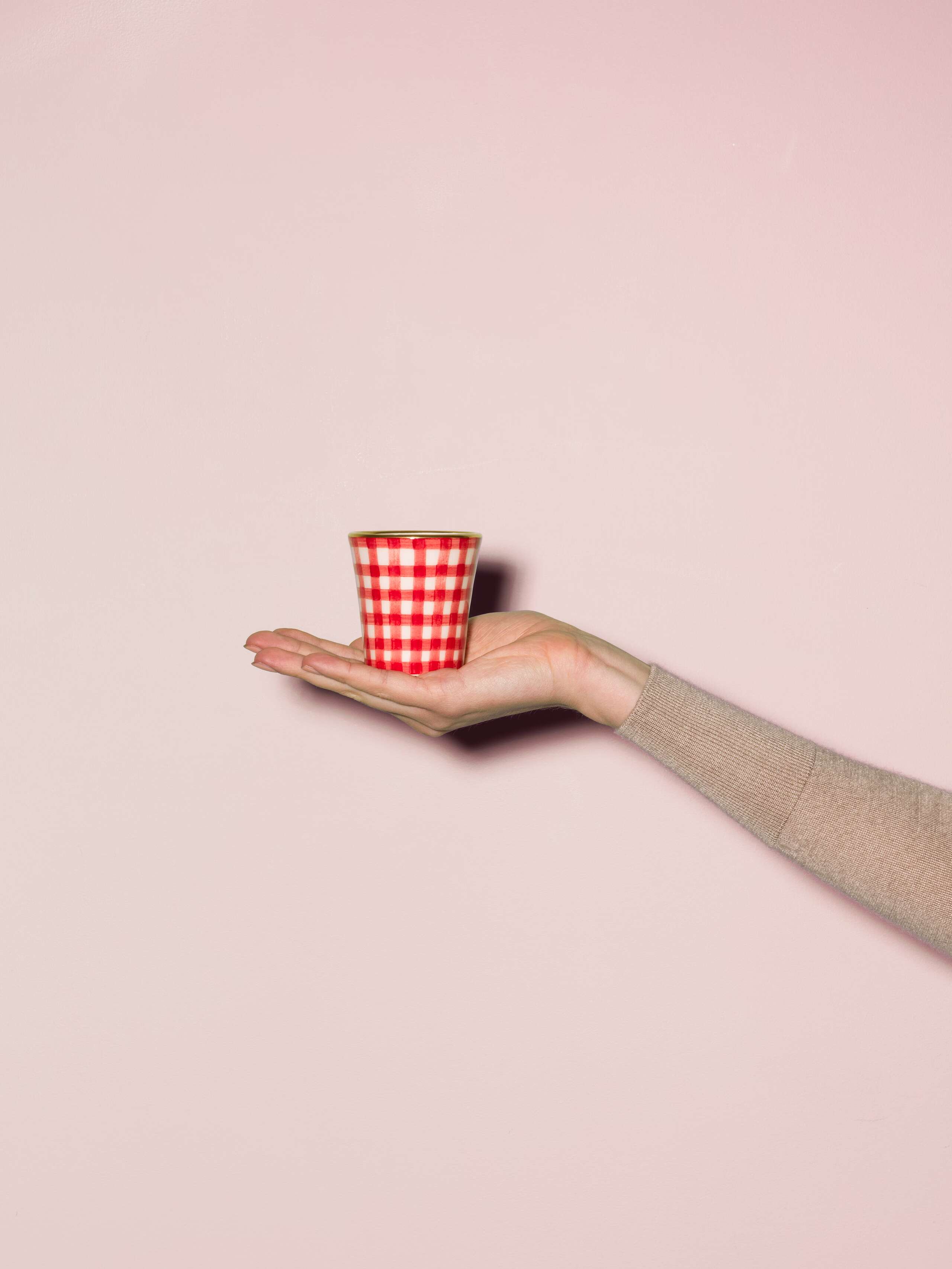 Picture of a hand made and hand printed espresso cup made of ceramic featuring a red vichy check pattern
