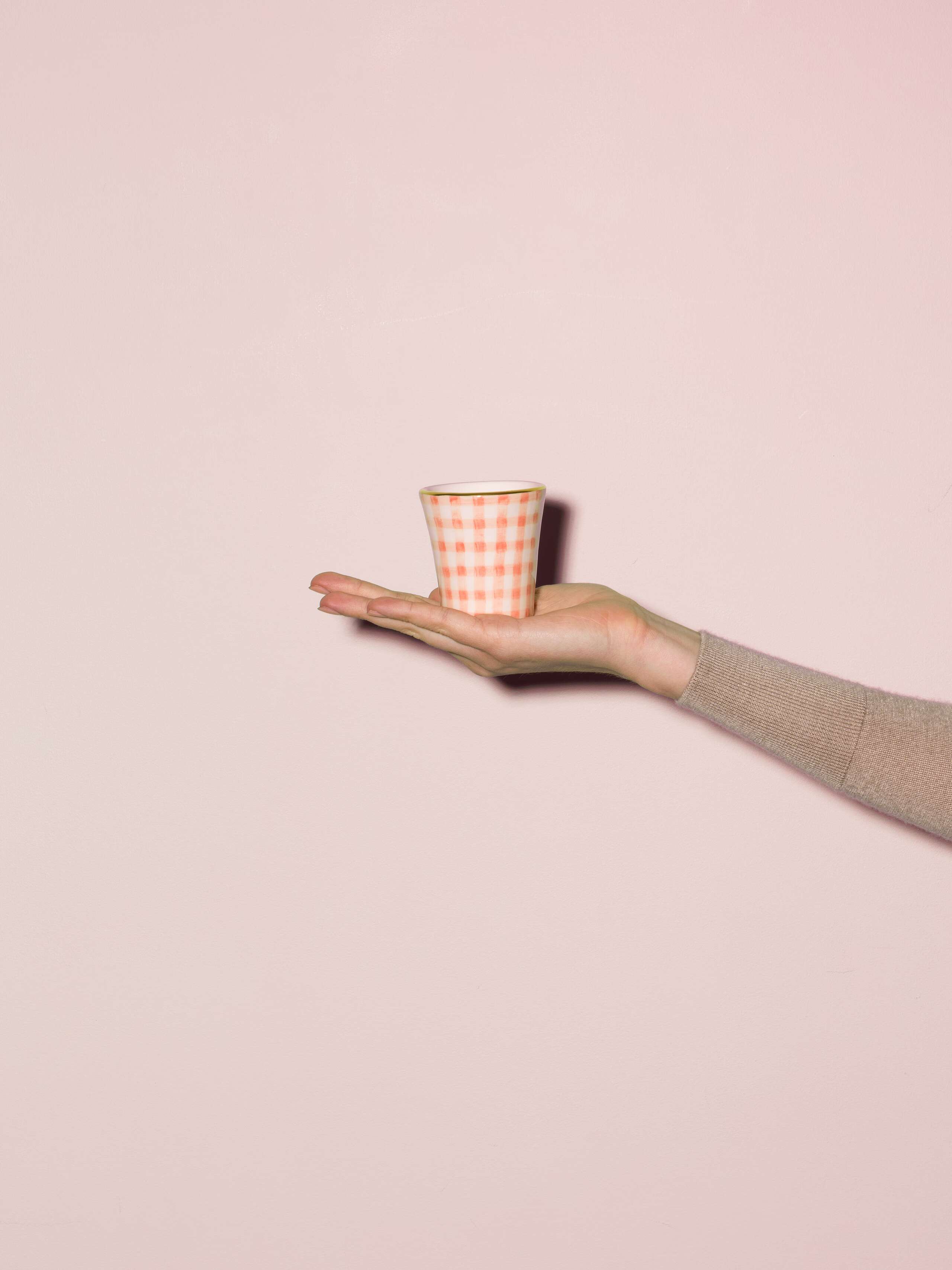 Picture of a hand made and hand printed espresso cup made of ceramic featuring a pink vichy check pattern