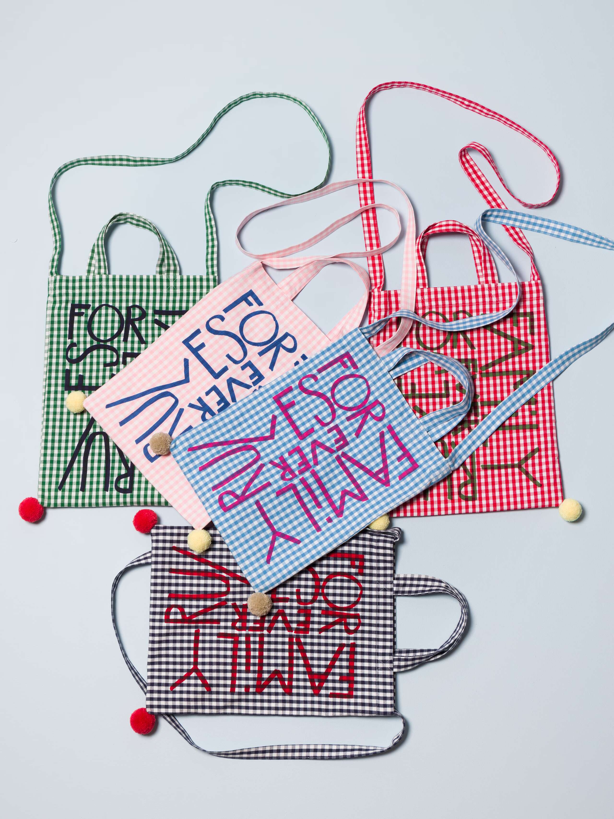 Five beautiful small tote bags featuring colourful pompoms and a family rules forever motto print