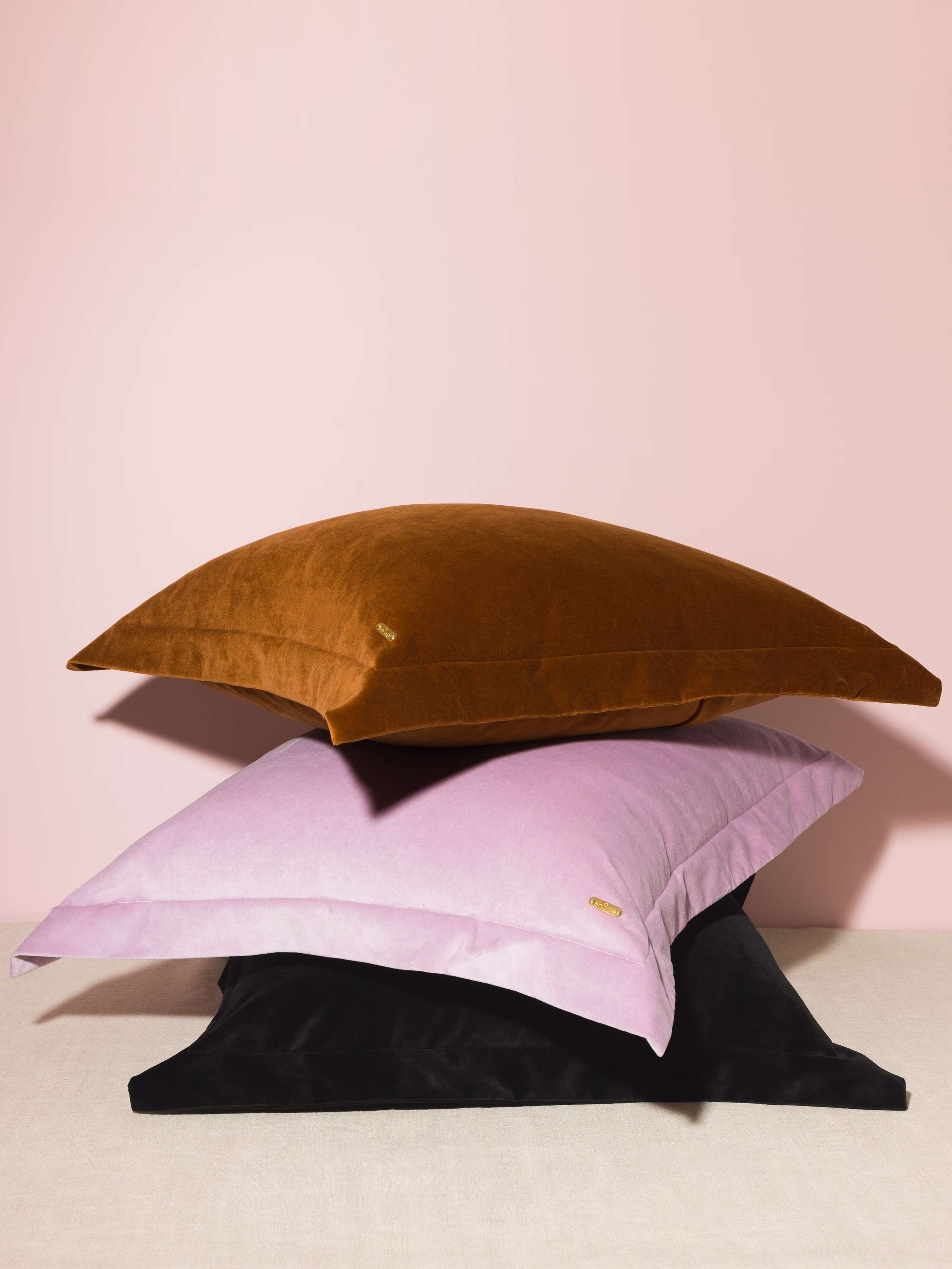 Picture of three beautiful pillow covers made of warm brown, light lilac and black cotton velvet