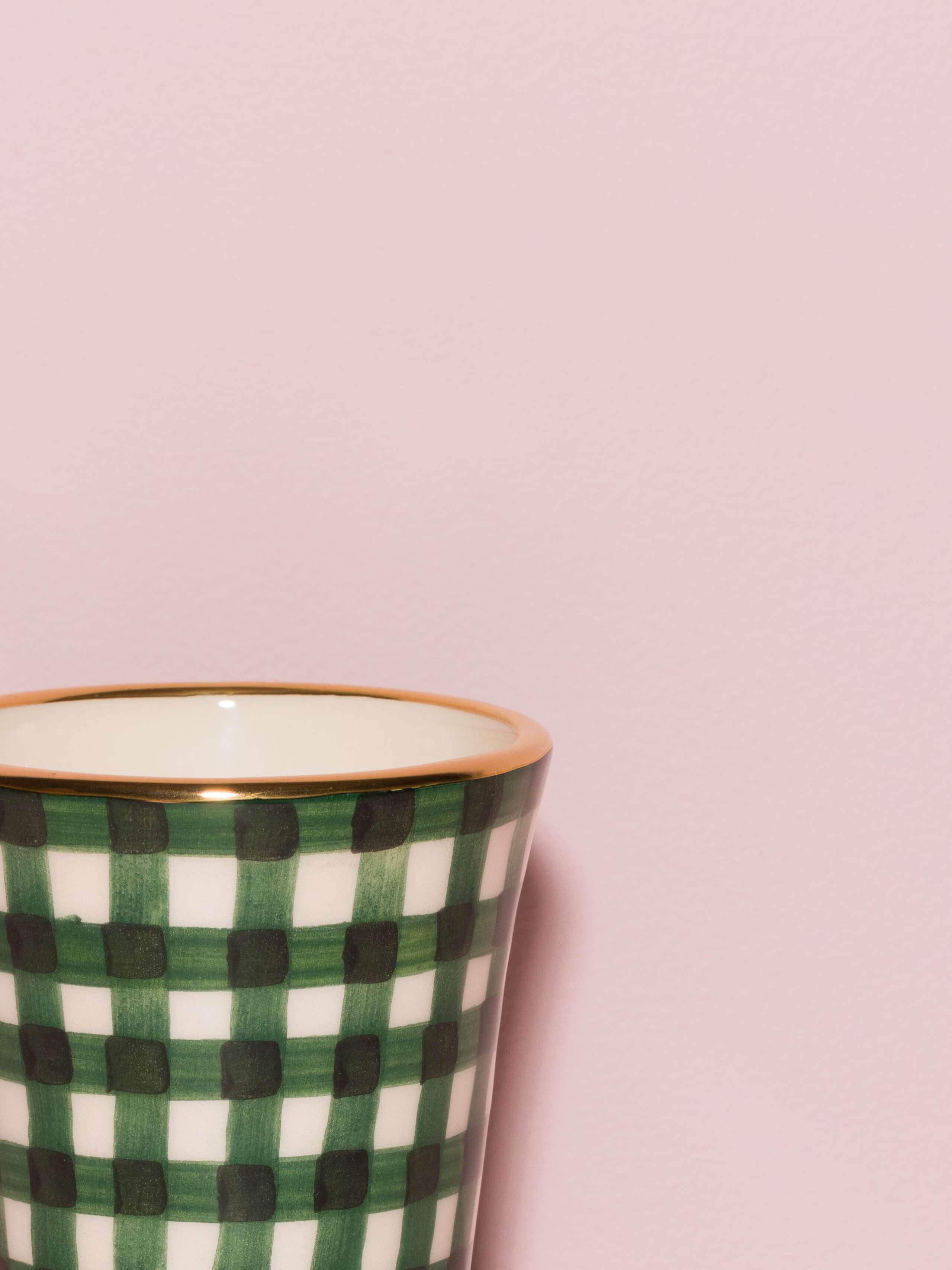 Picture of a detail of an espresso cup featuring a golden rim and a green vichy check pattern