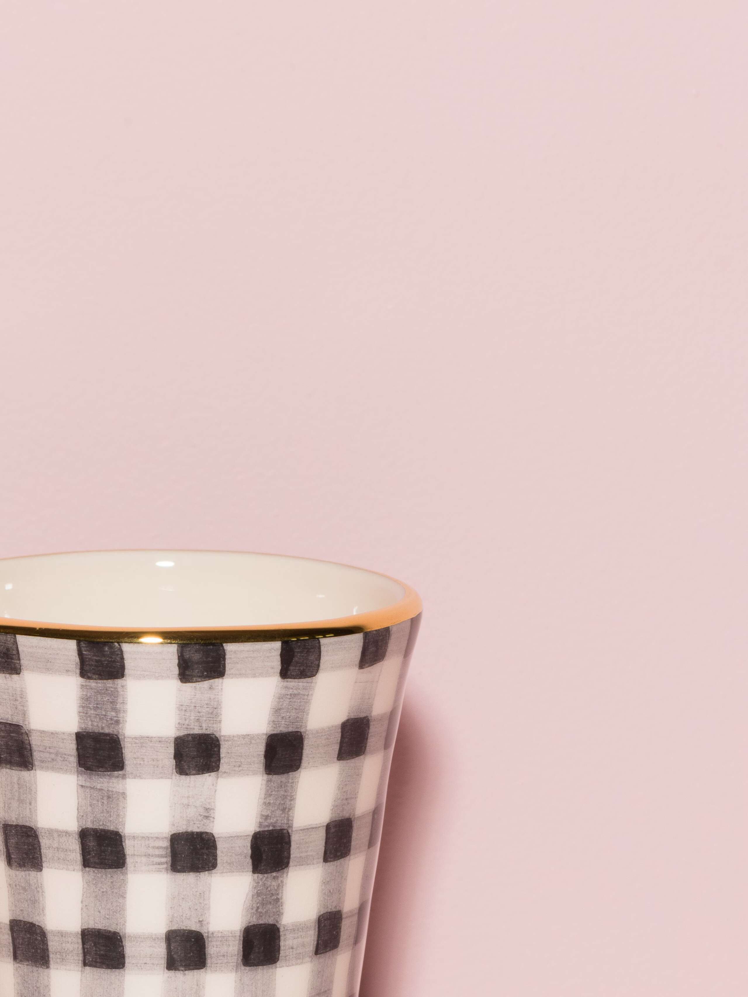 Picture of a detail of an espresso cup featuring a golden rim and a green vichy check pattern
