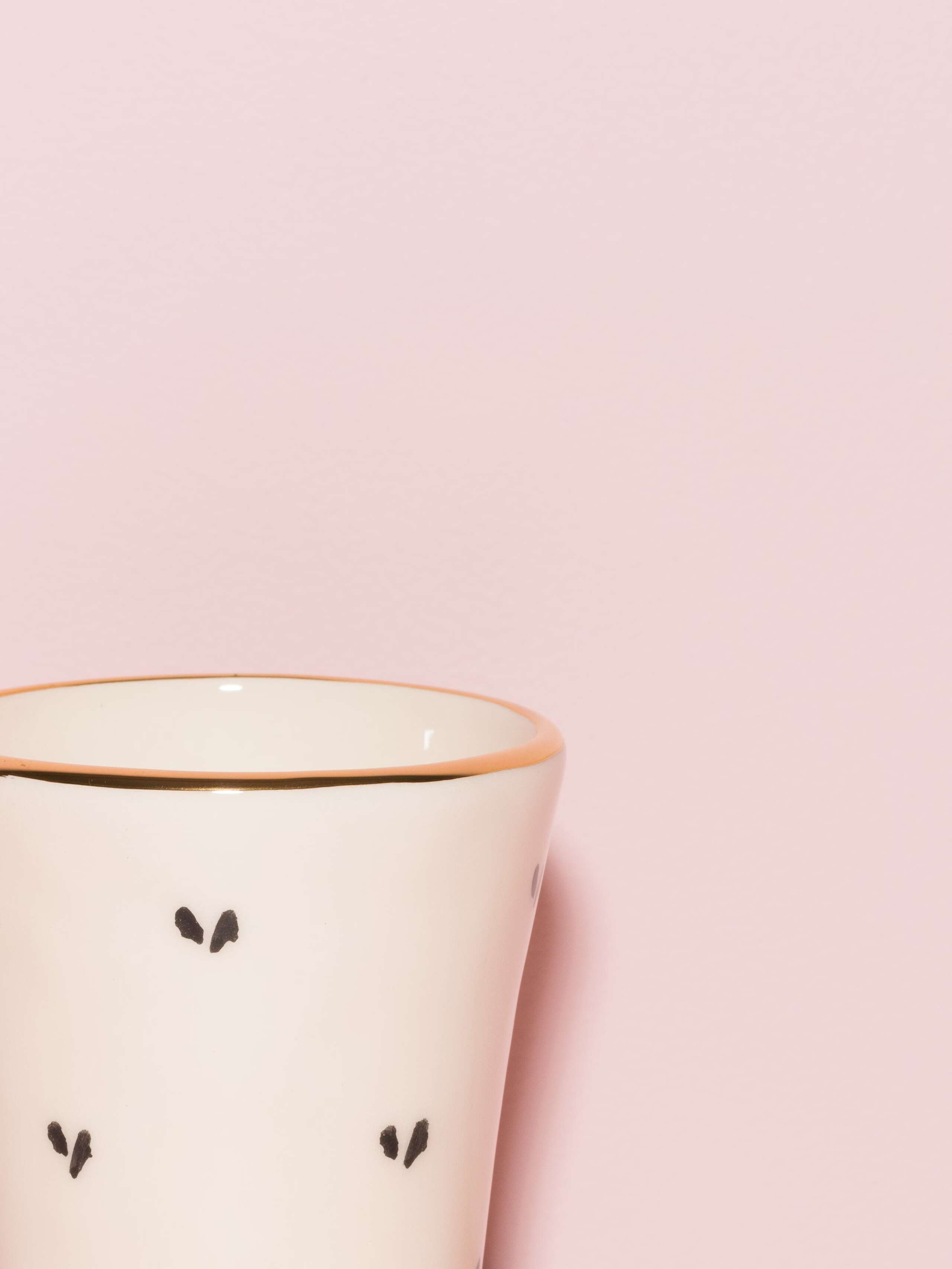 Picture of a detail of an espresso cup featuring a golden rim and a heart pattern