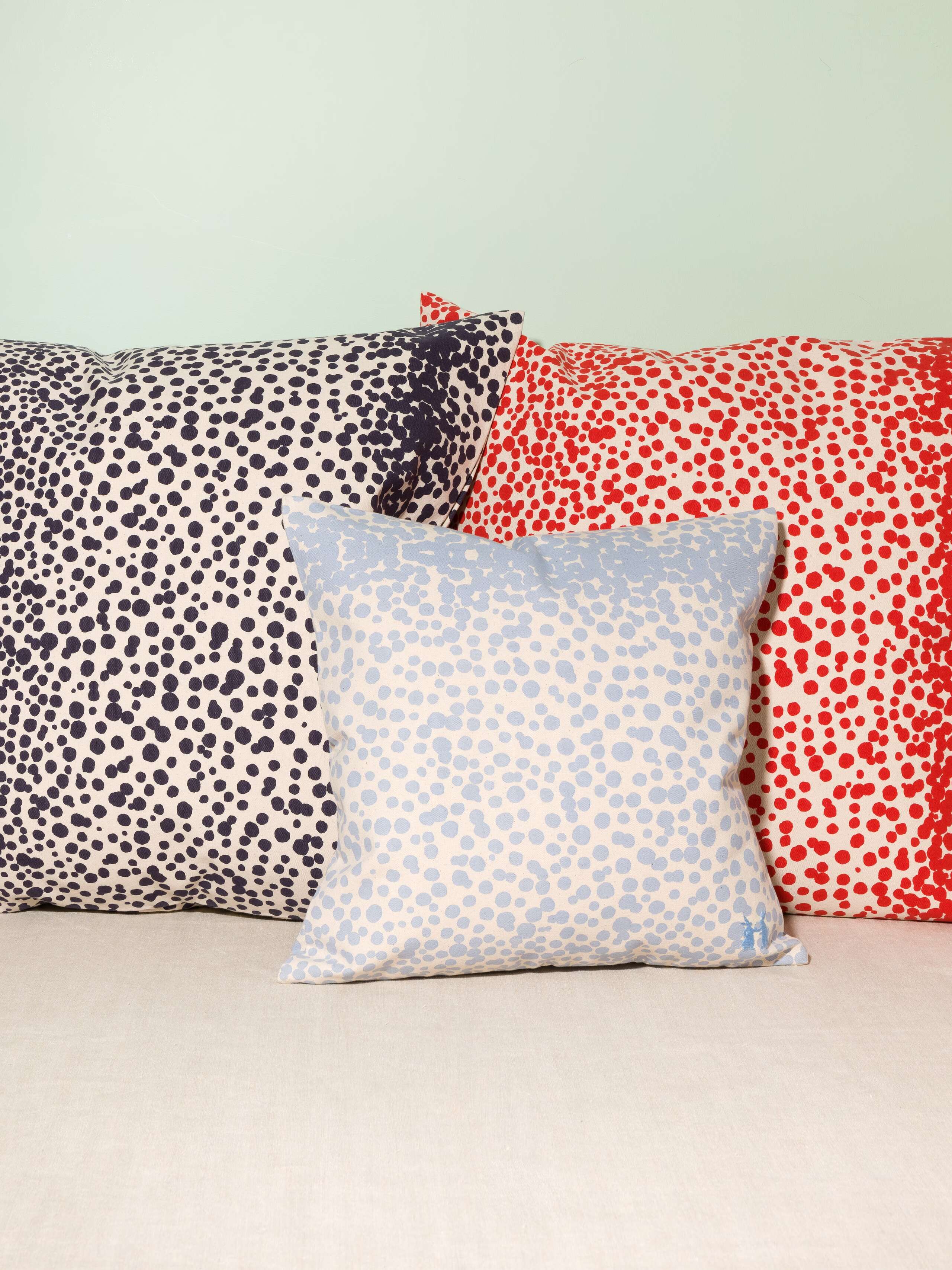 Picture of four pillow covers made of cotton canvas featuring pink, navy blue and red dots