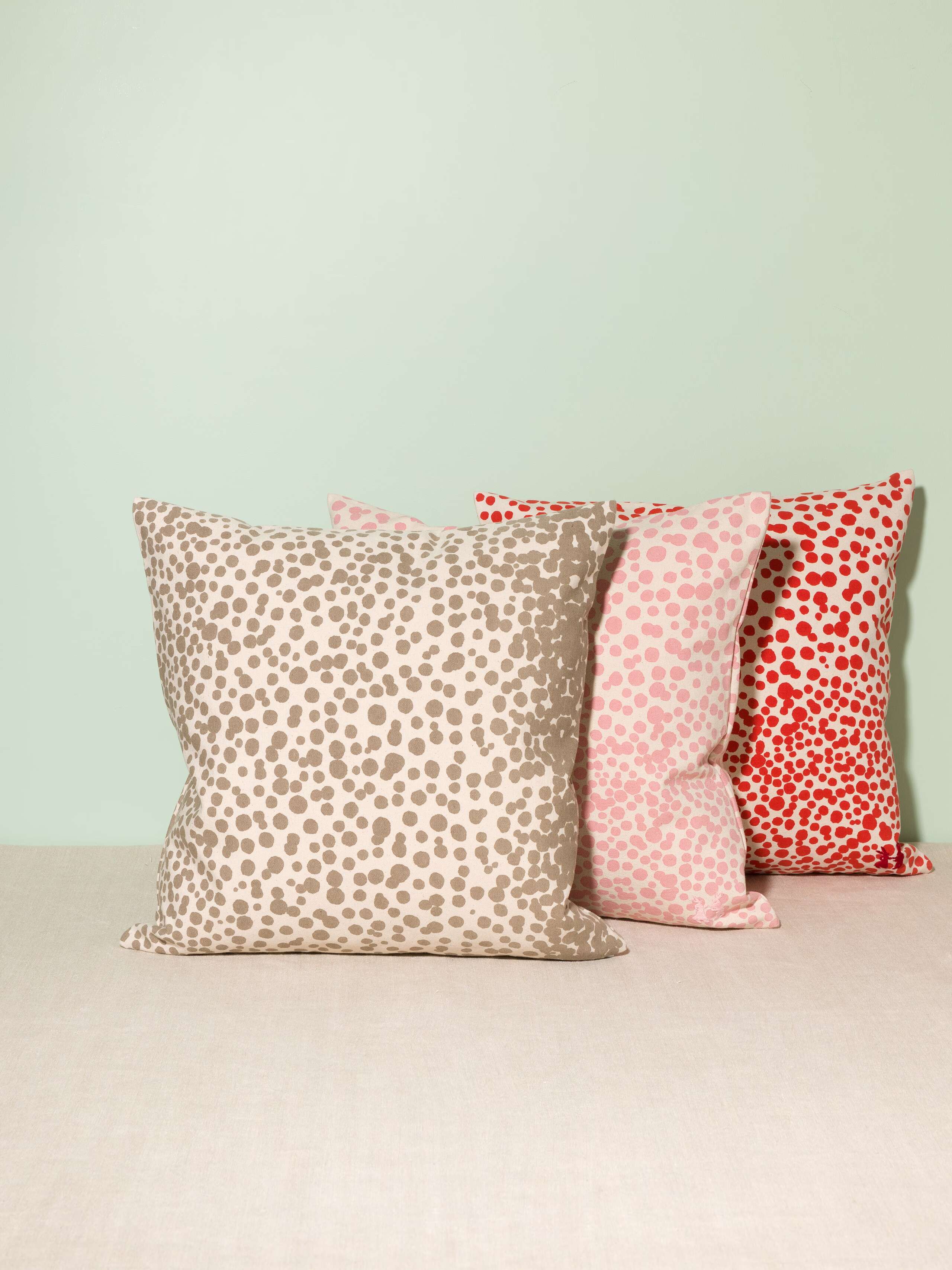 Picture of three pillow covers made of cotton canvas featuring red, pink and beige dots