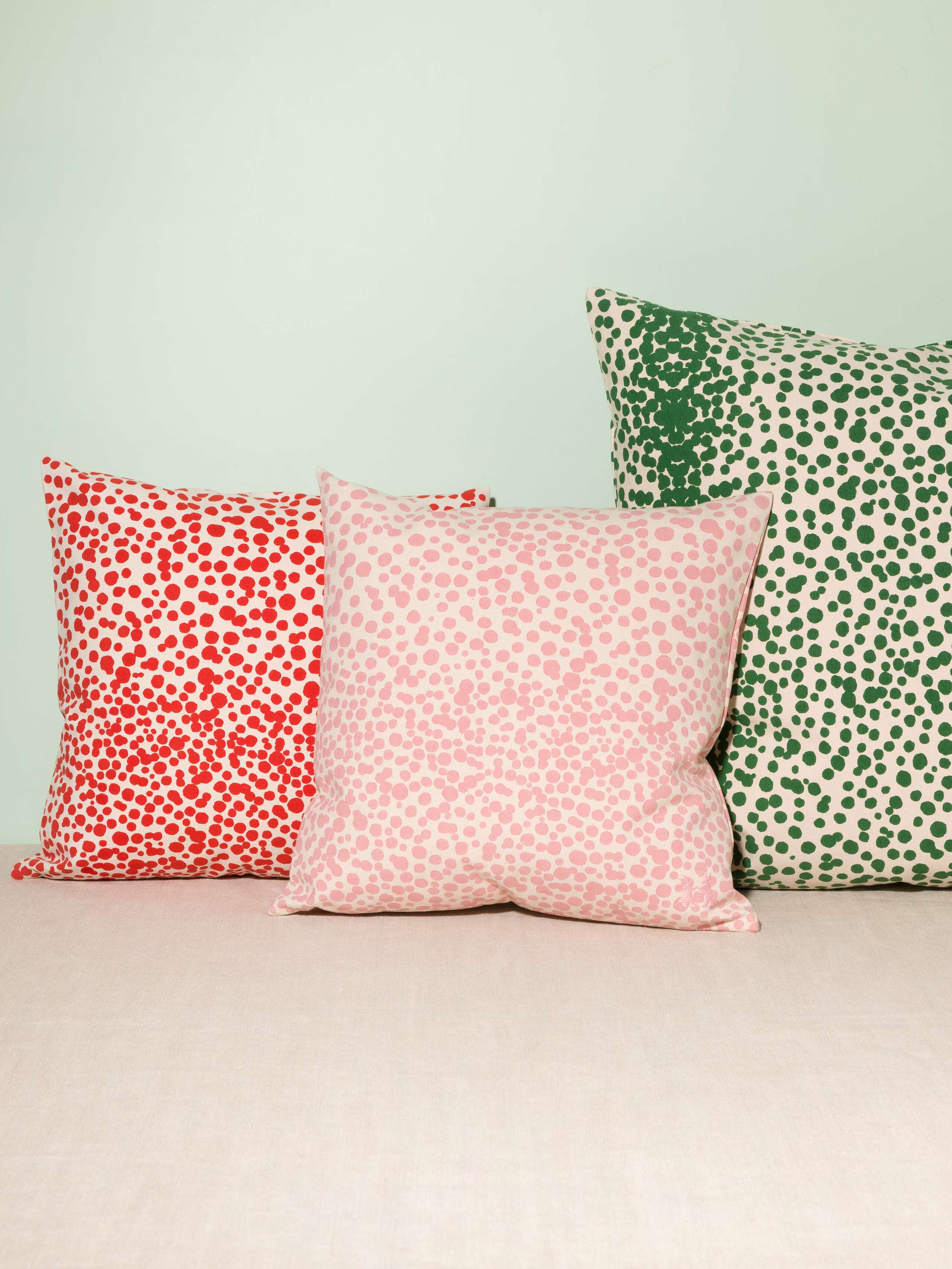 Picture of three pillow covers made of cotton canvas featuring red, pink and green dots