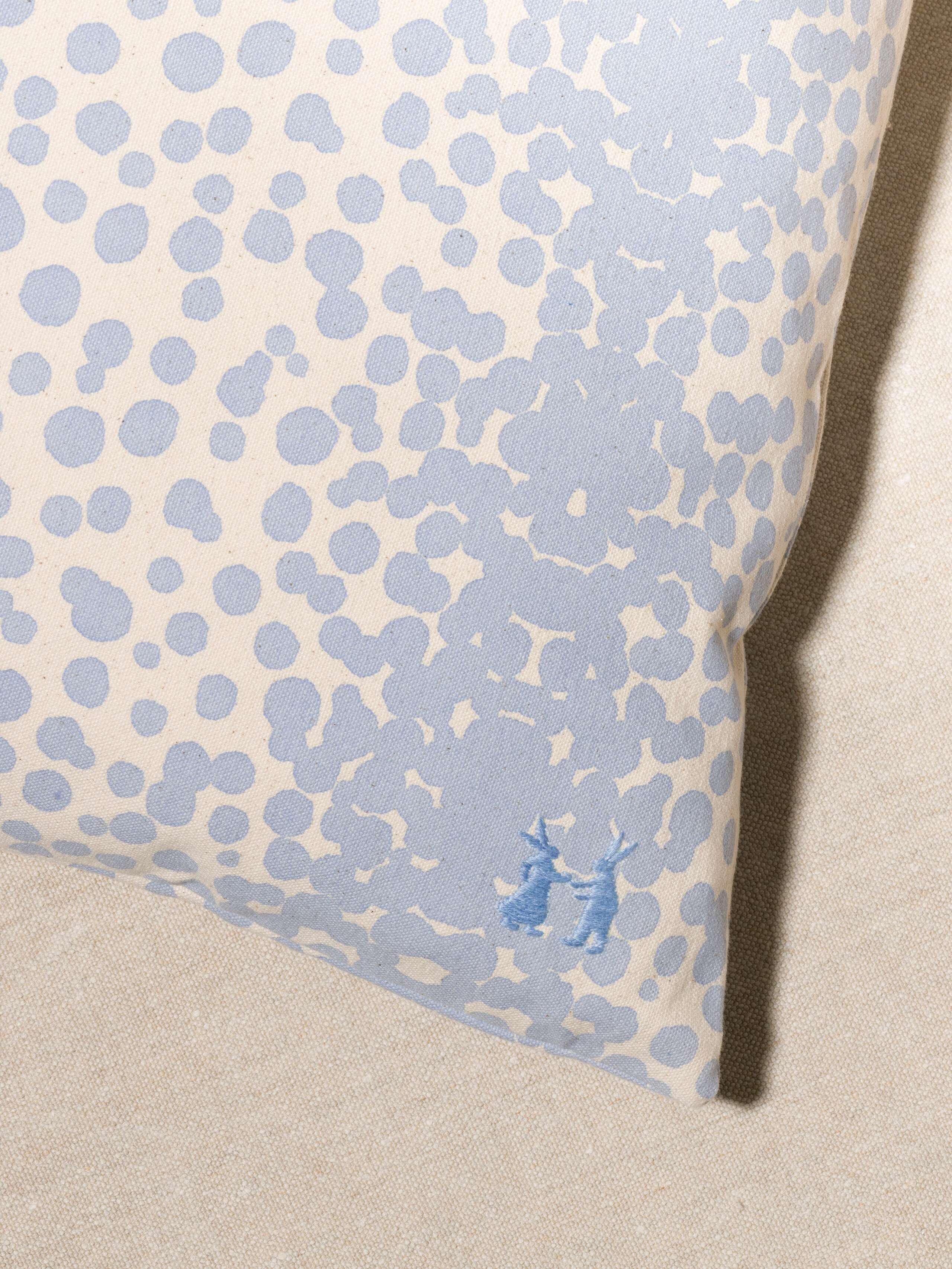 Picture of a detail of a pillow cover made from cotton canvas featuring light blue dots