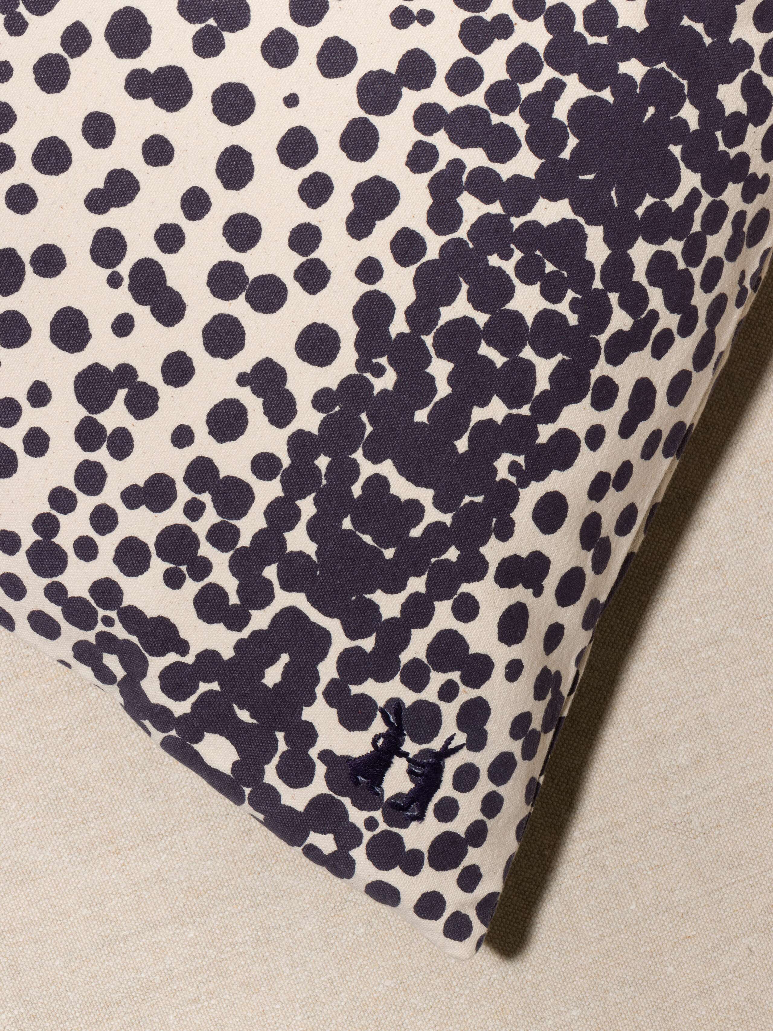 Picture of a detail of a pillow cover made from cotton canvas featuring navy blue dots