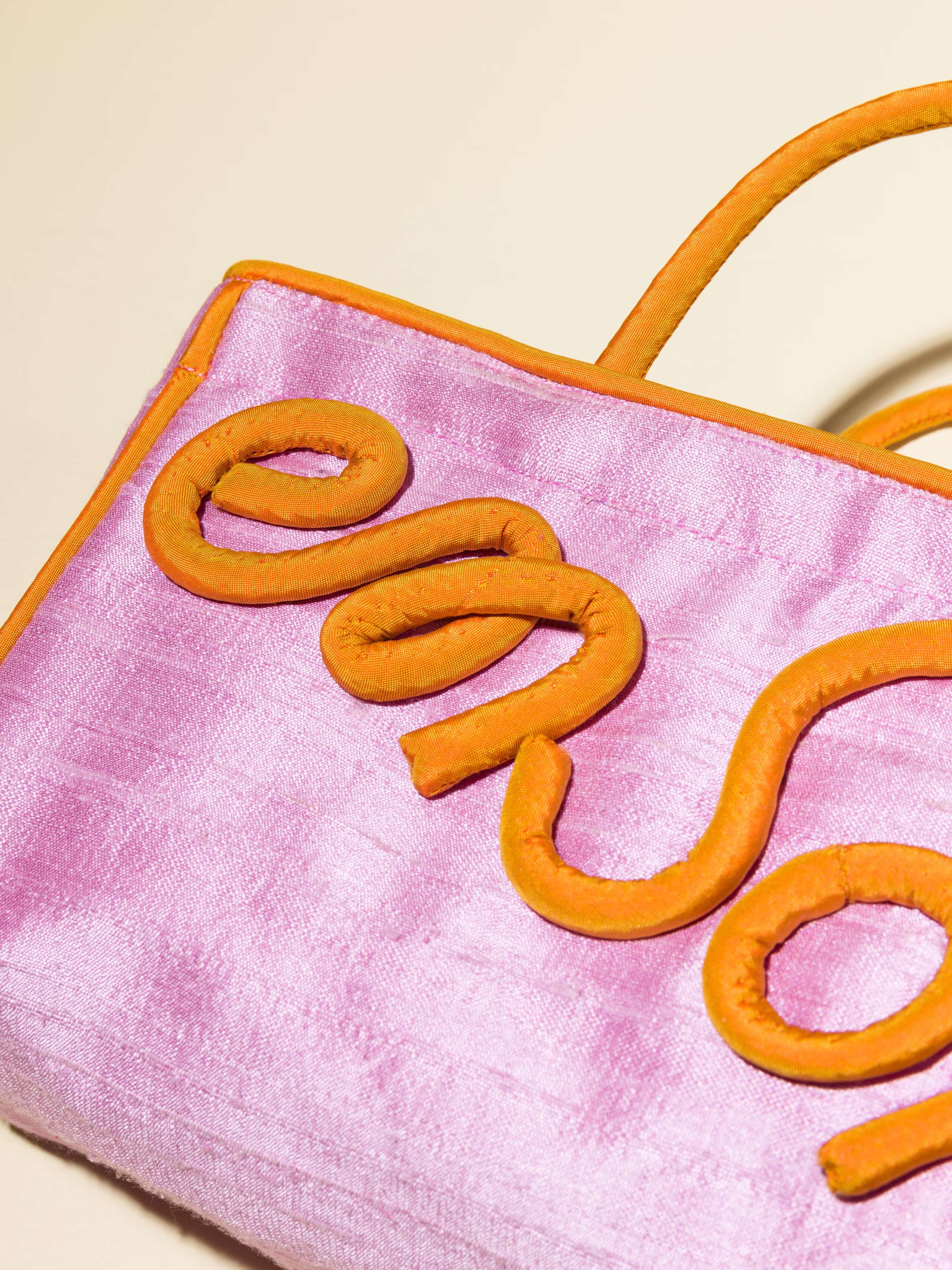 Picture of a detail of a lavender silk bag with orange details