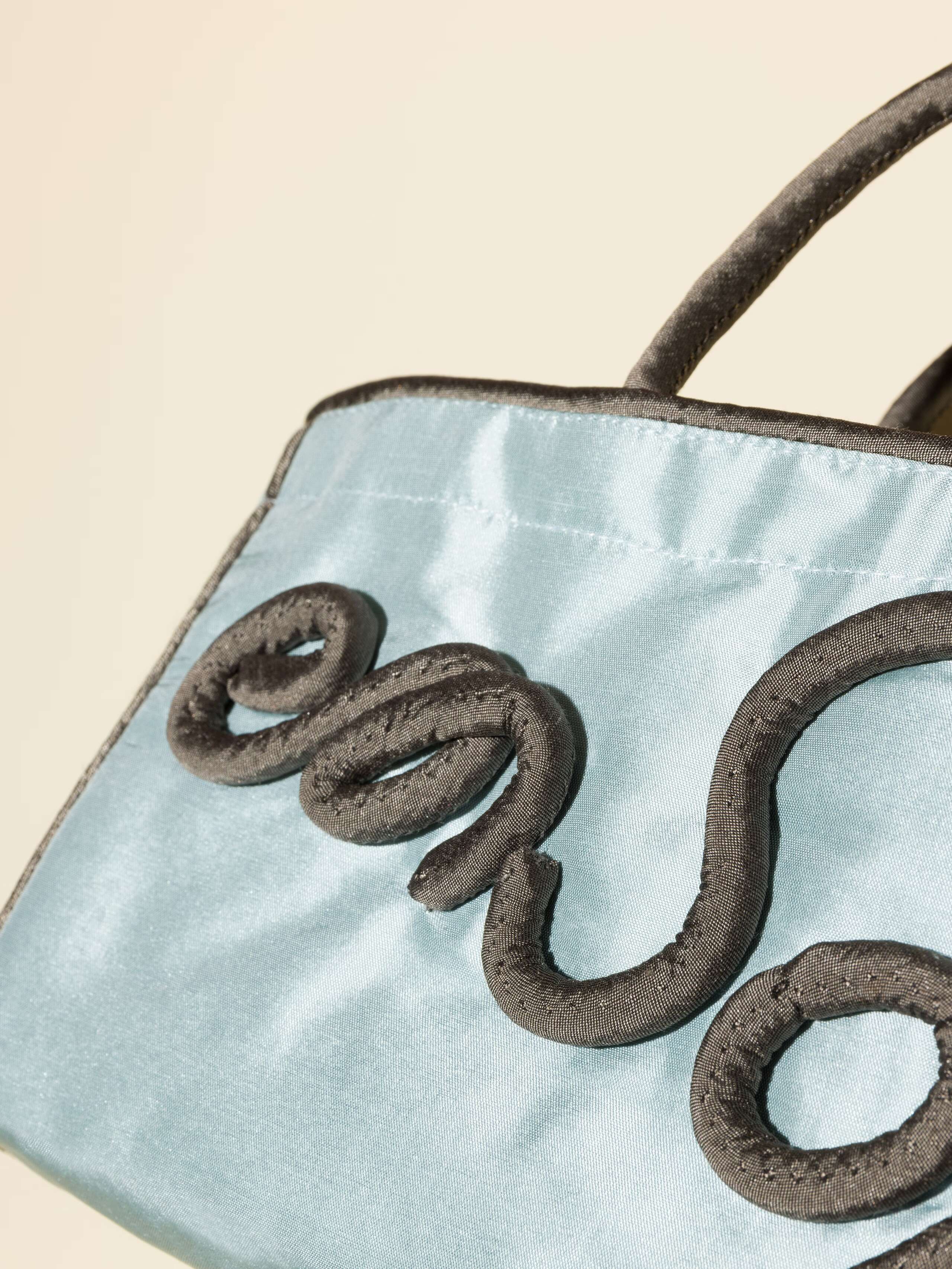 Picture of a detail of a light blue silk bag with green details