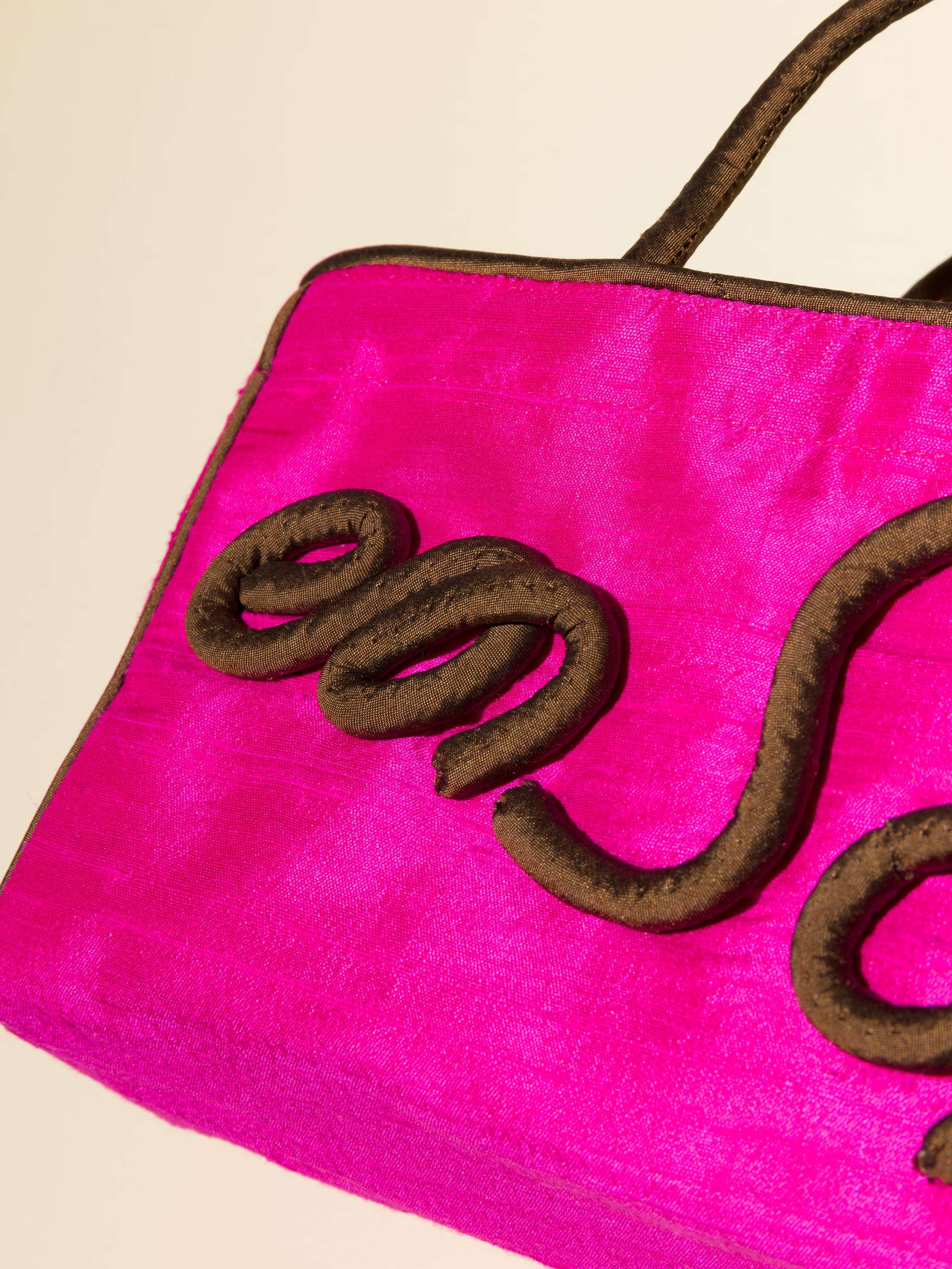 Picture of a detail of a pink silk bag with brown details