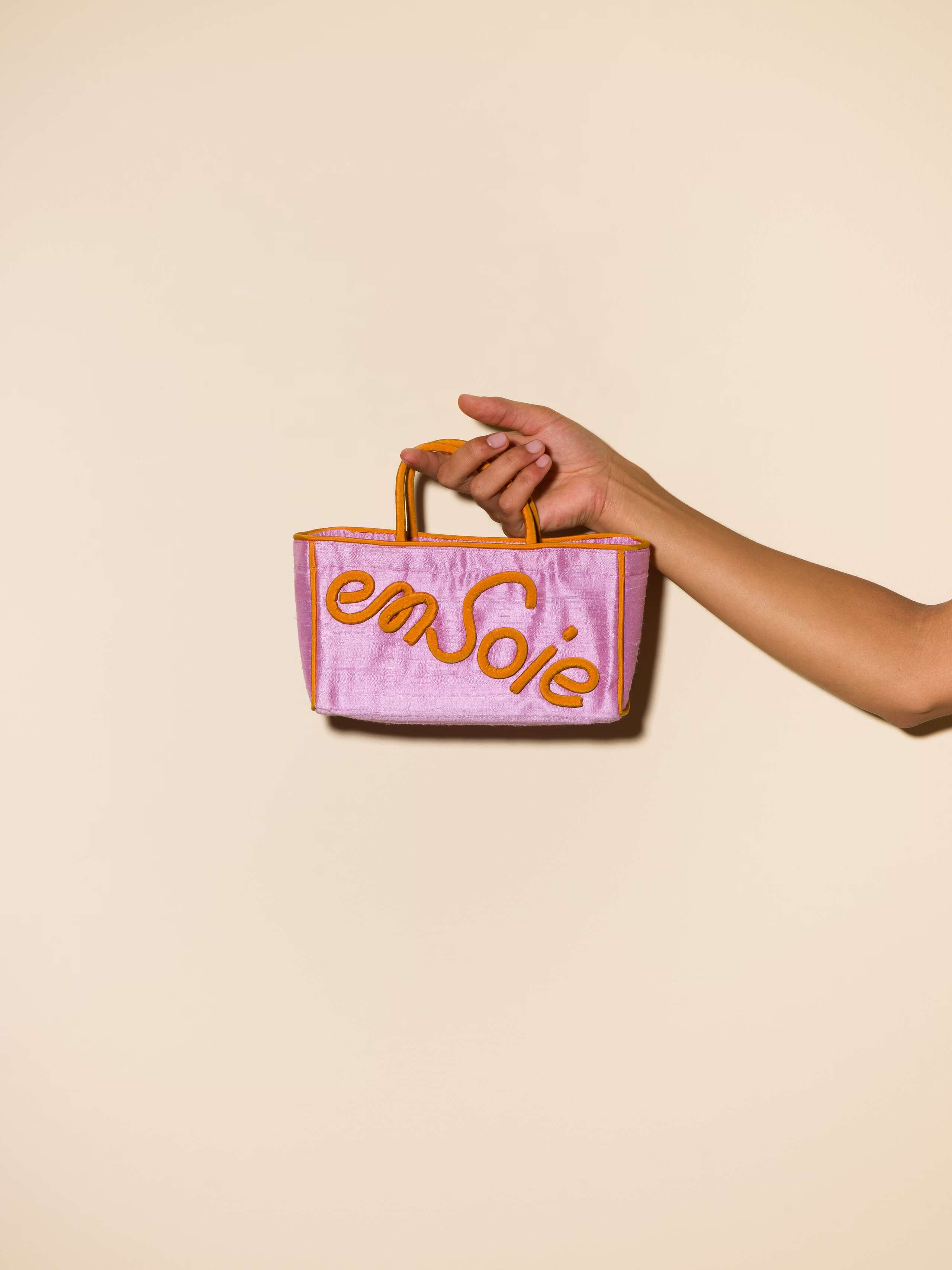 Picture of a lavender coloured silk micro hand bag with orange details