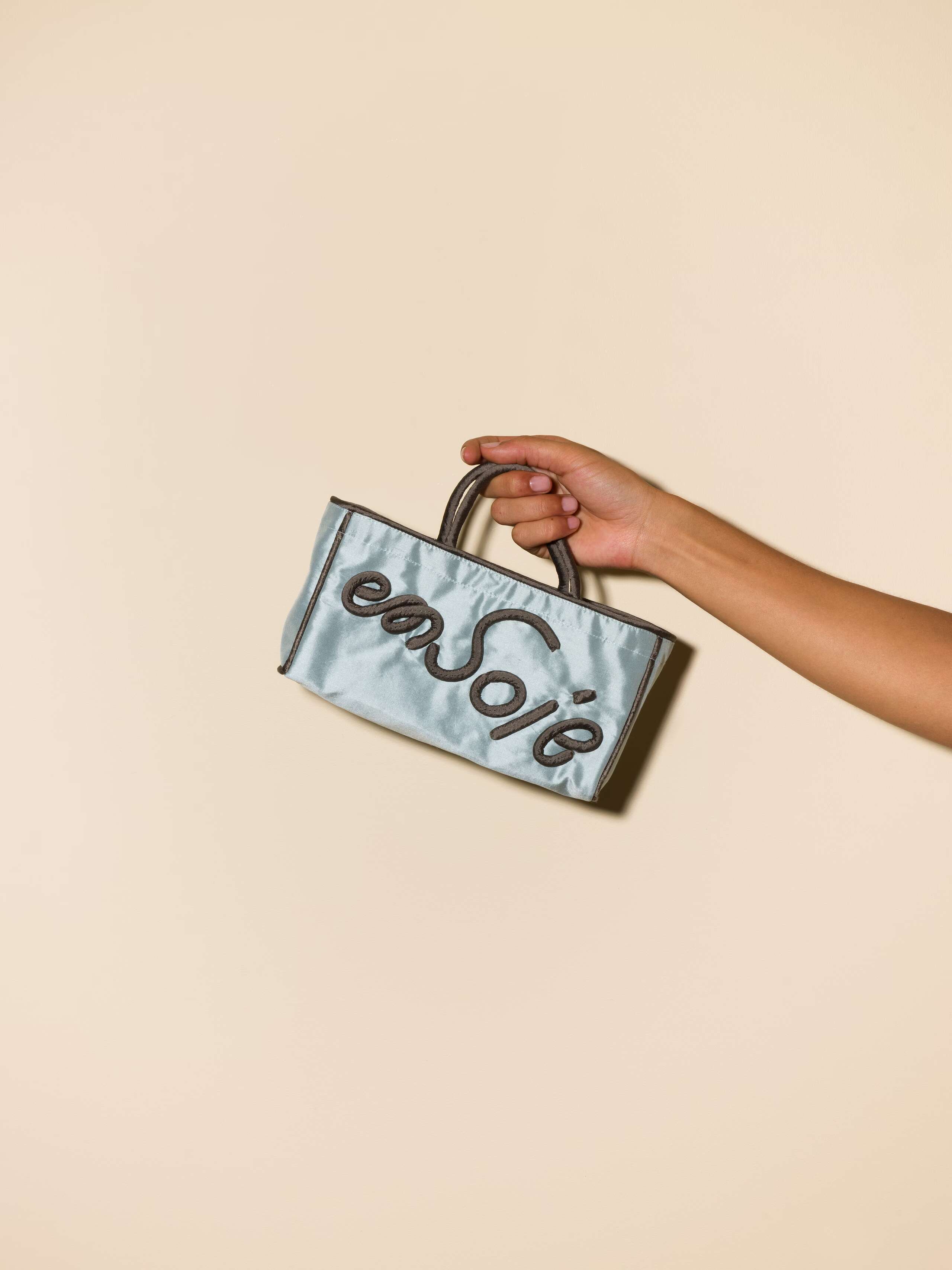 Picture of a light blue silk hand bag with green details
