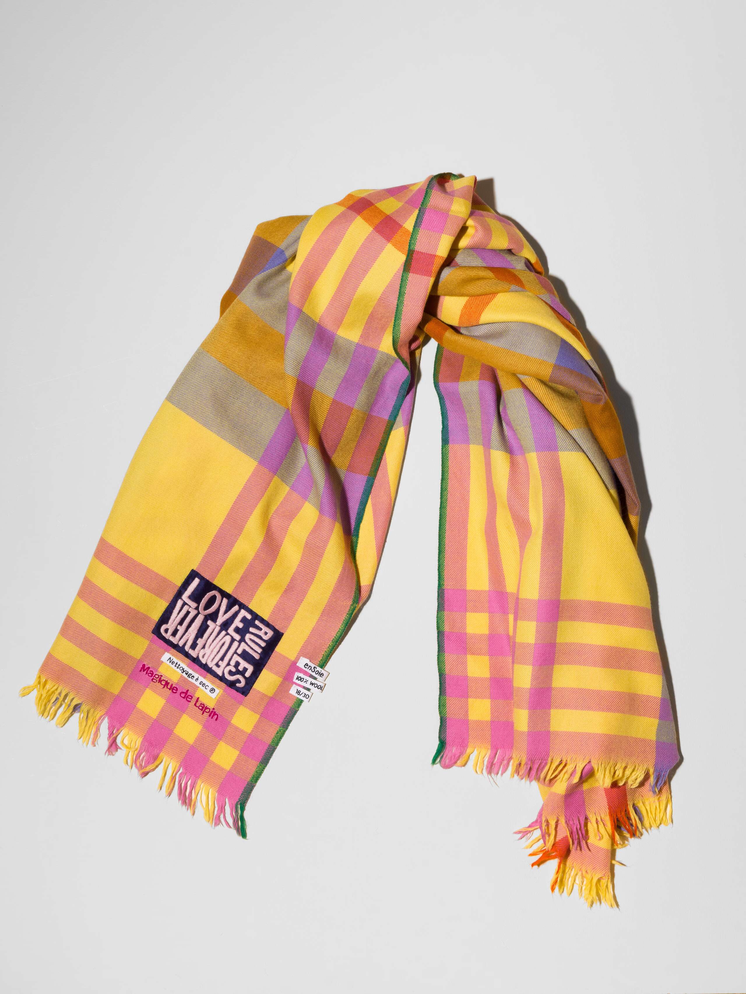 Picture of a detail of a wool scarf in a sunny yellow shade featuring a pink and lilac check pattern