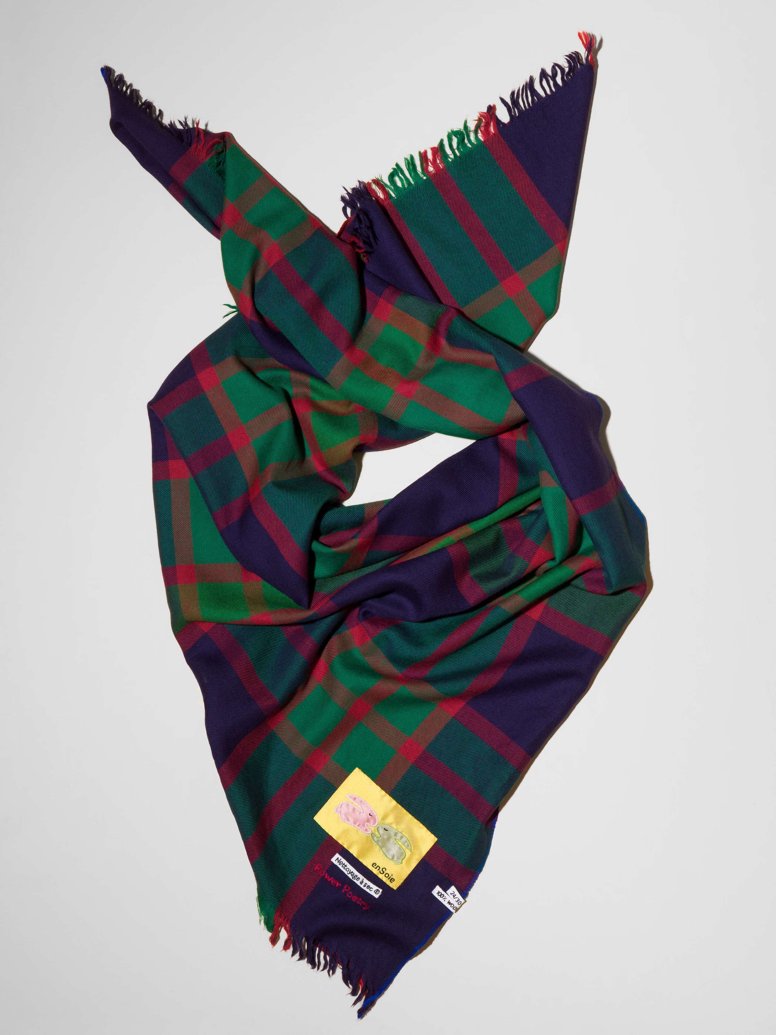 Picture of a wool scarf in a dark navy tone featuring a check pattern in green and red shades