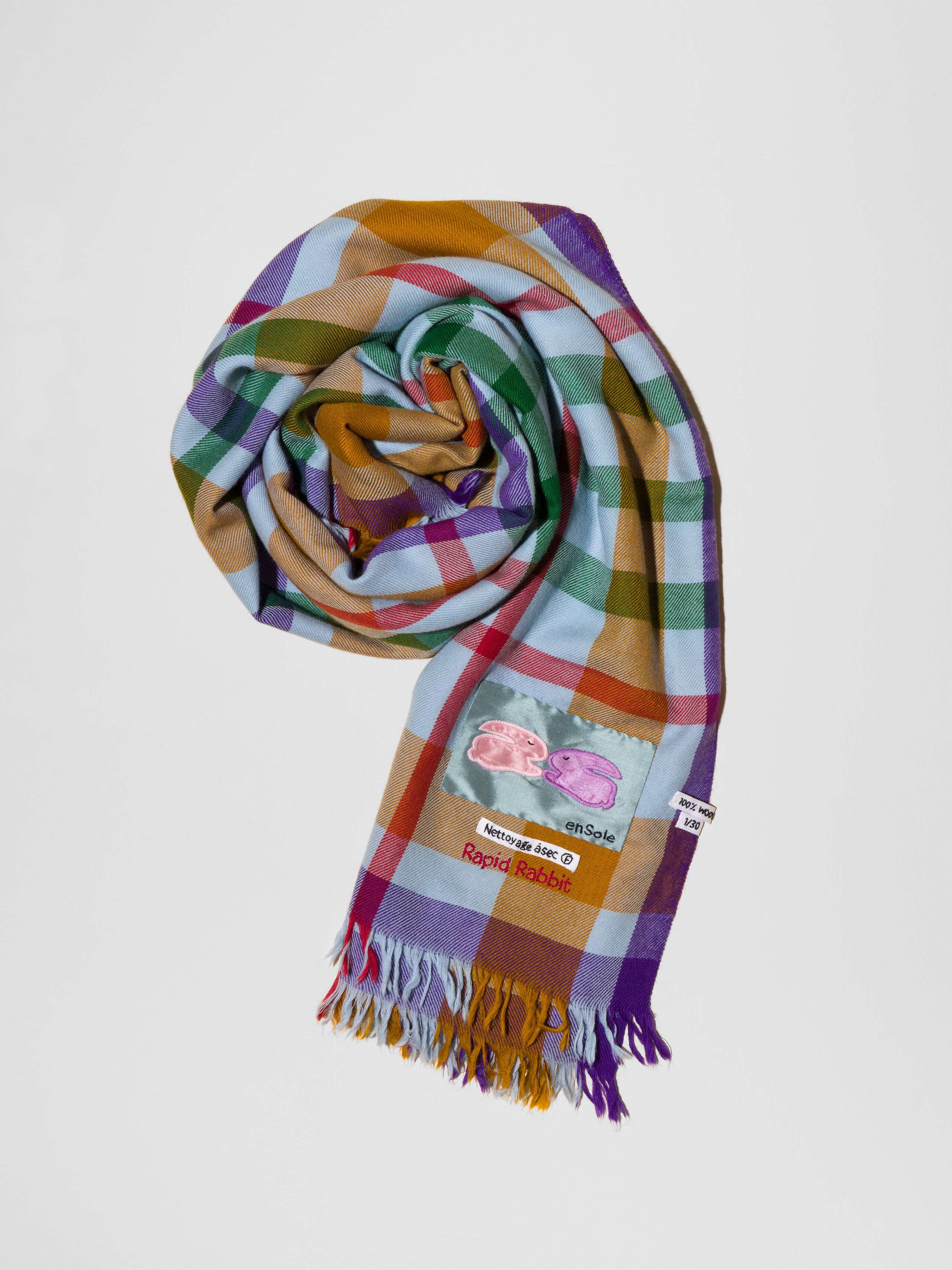 Picture of a wool scarf in a beautiful blue grey shade featuring a check pattern in green, purple, brown and red shades