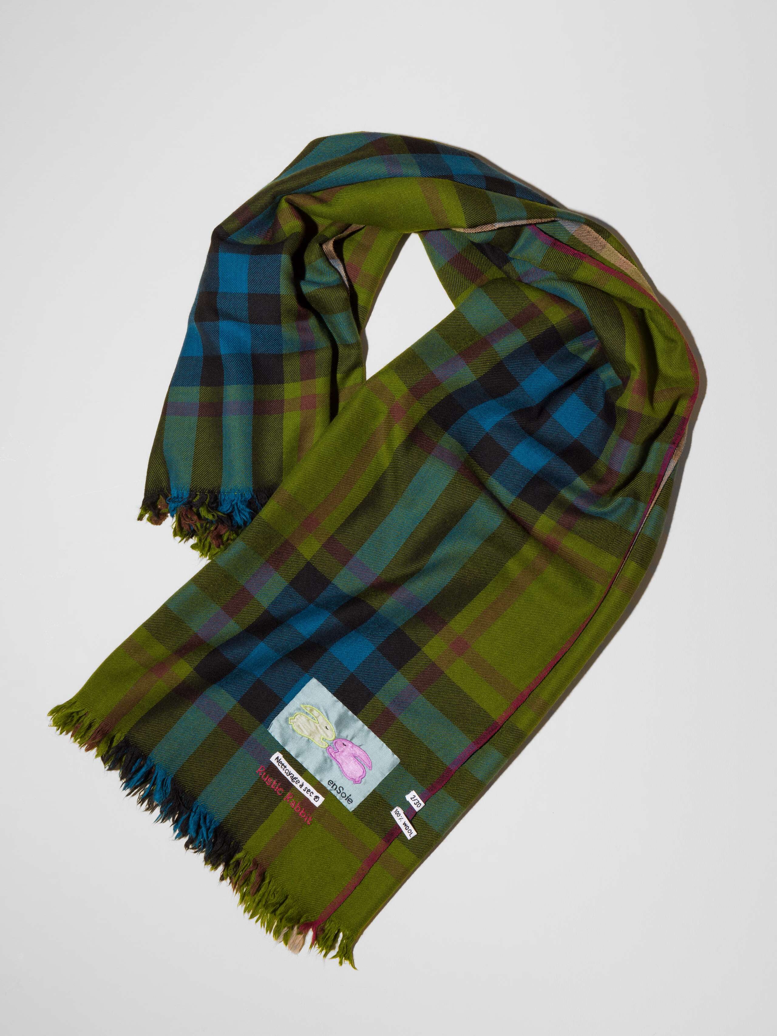 Picture of a wool scarf in a beautiful olive green shade featuring a check pattern in petrol blue and bordeaux red shades