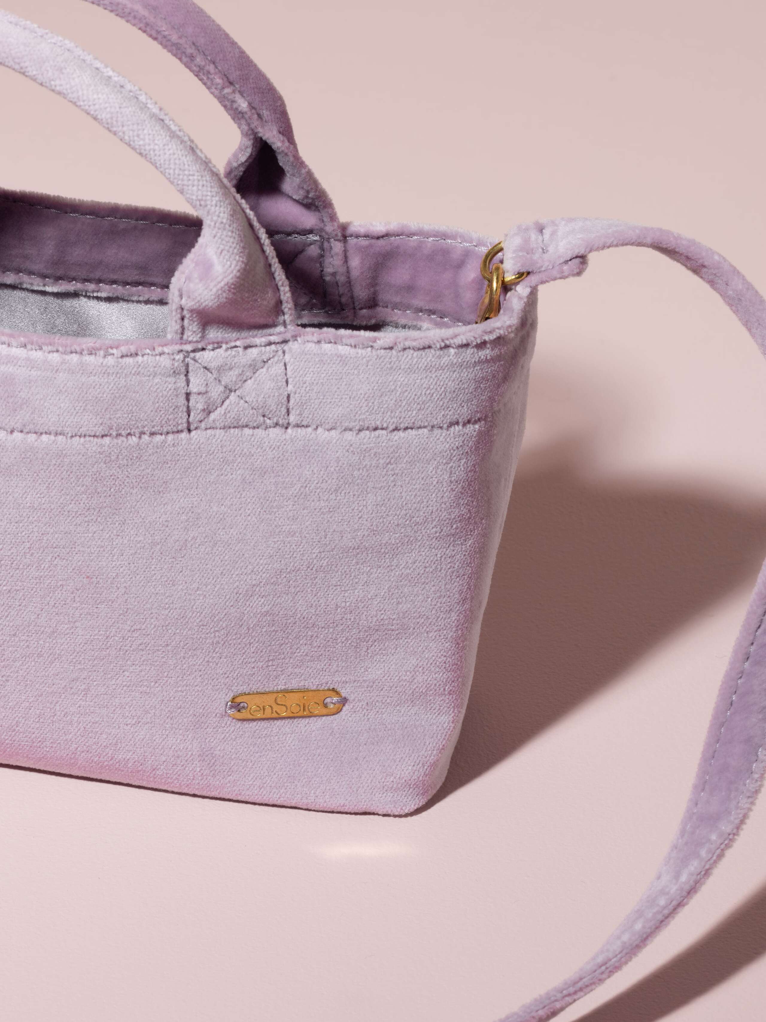 Picture of a detail of a small handbag made of lavender coloured velvet fabric