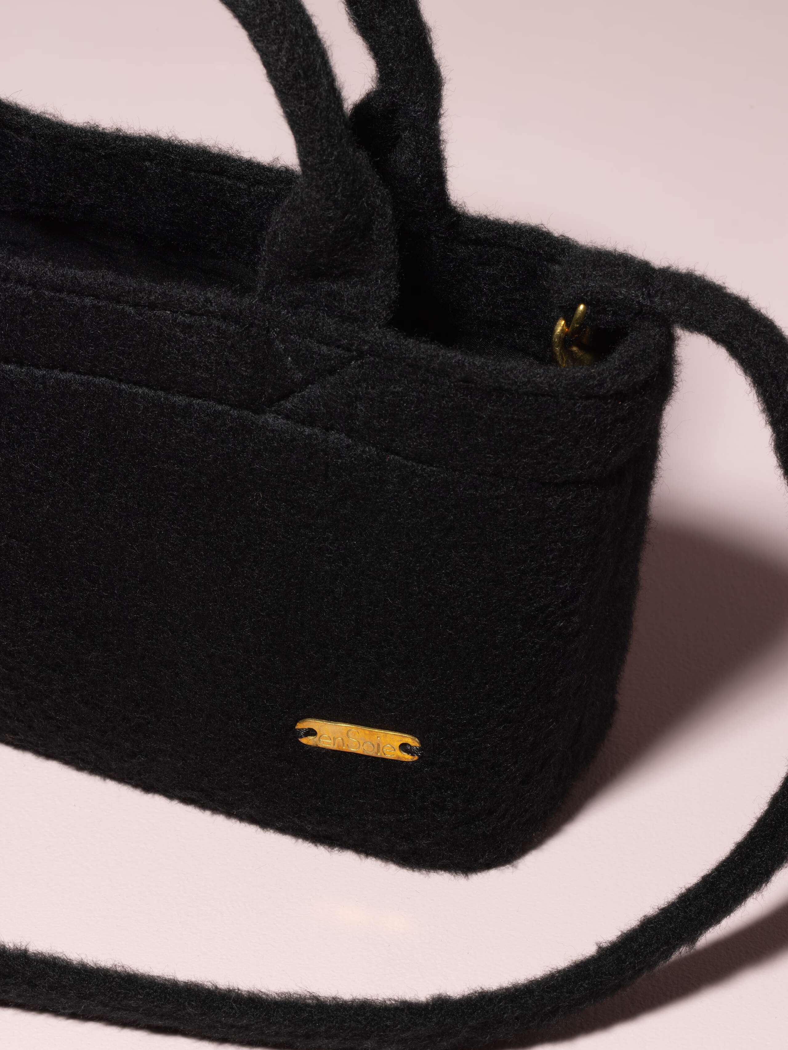 Picture of a detail of a small hand bag made of black wool tweed fabric