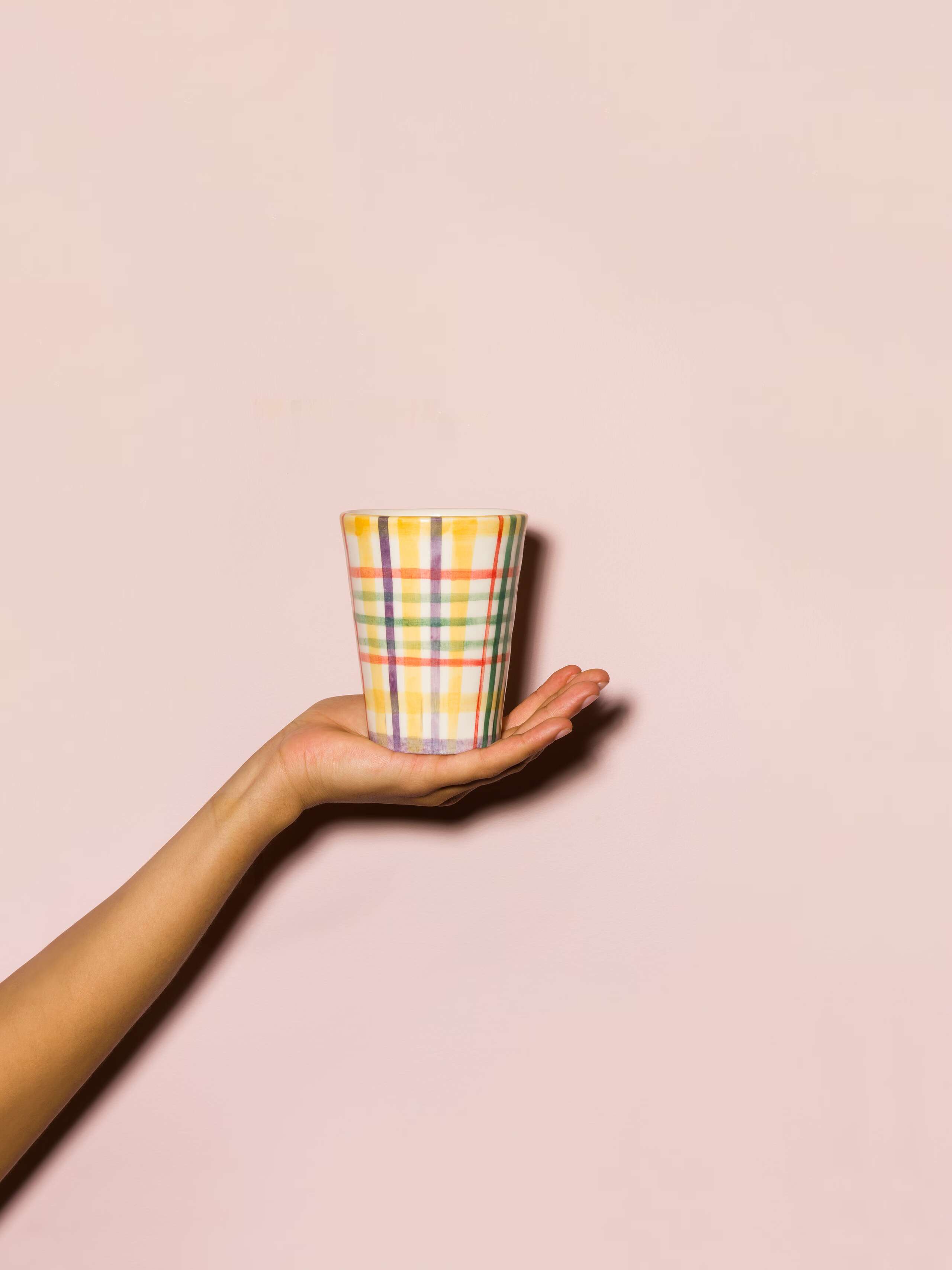 Picture of a hand holding a colourful hand painted cup