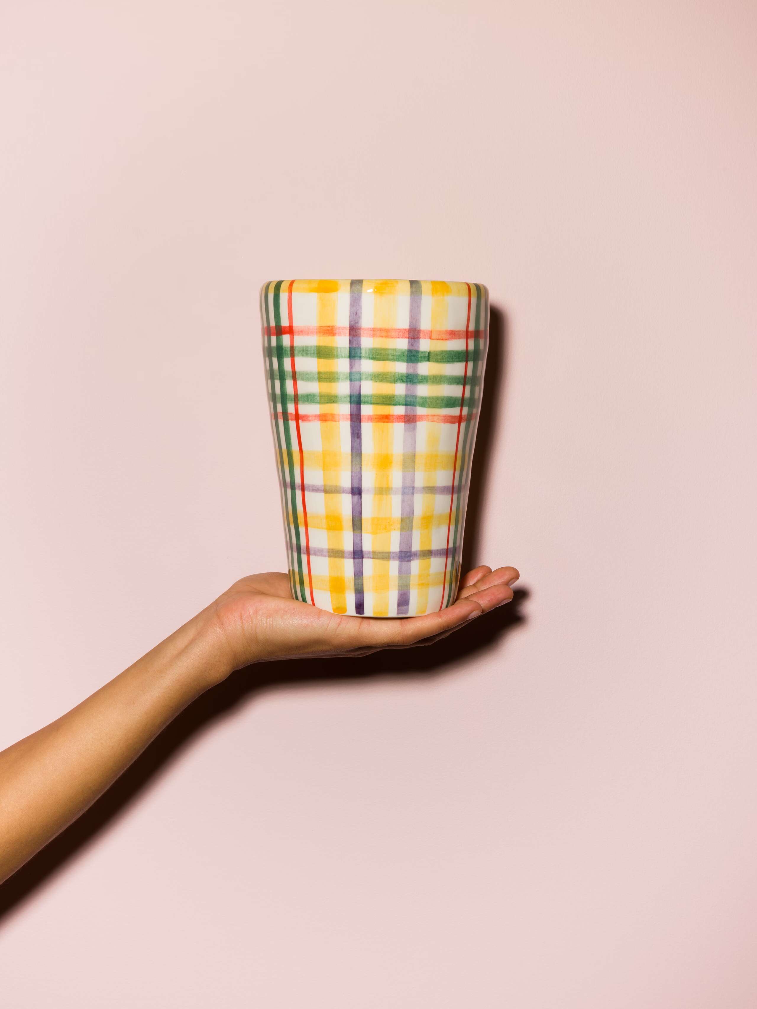 Picture of a hand holding a colourful hand printed vase