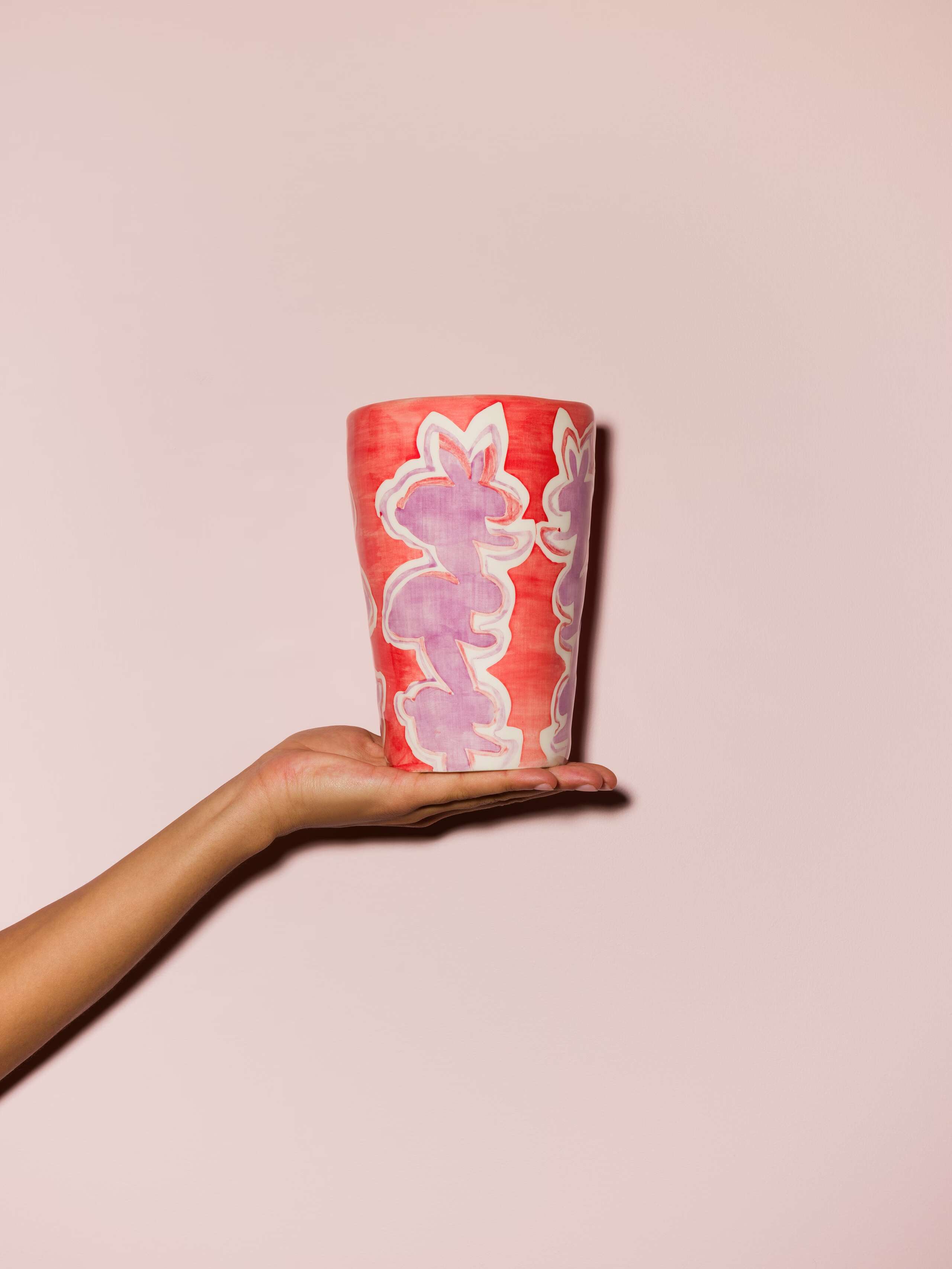 Picture of a hand holding a colourful hand printed vase
