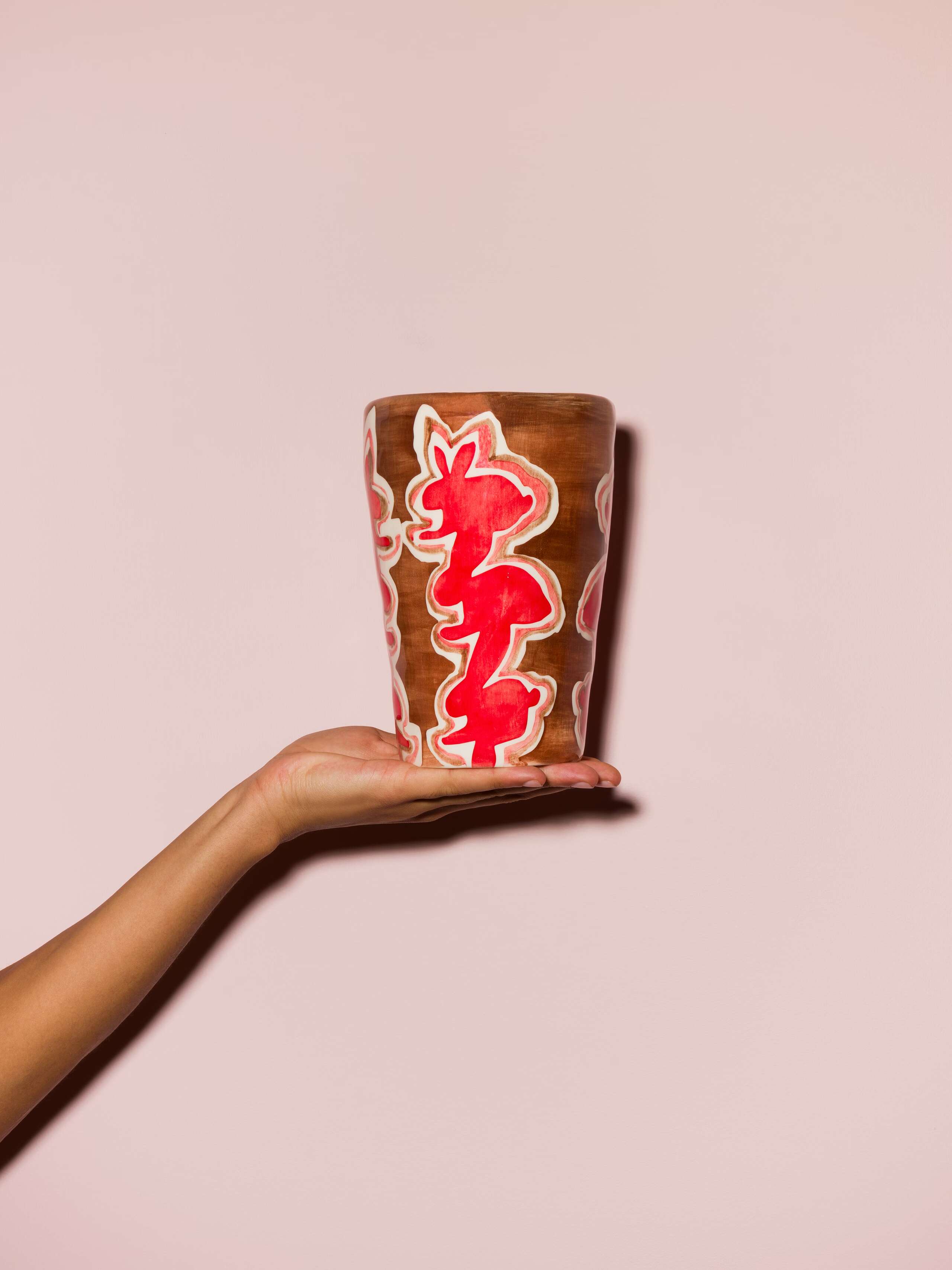 Picture of a hand holding a colourful hand printed vase
