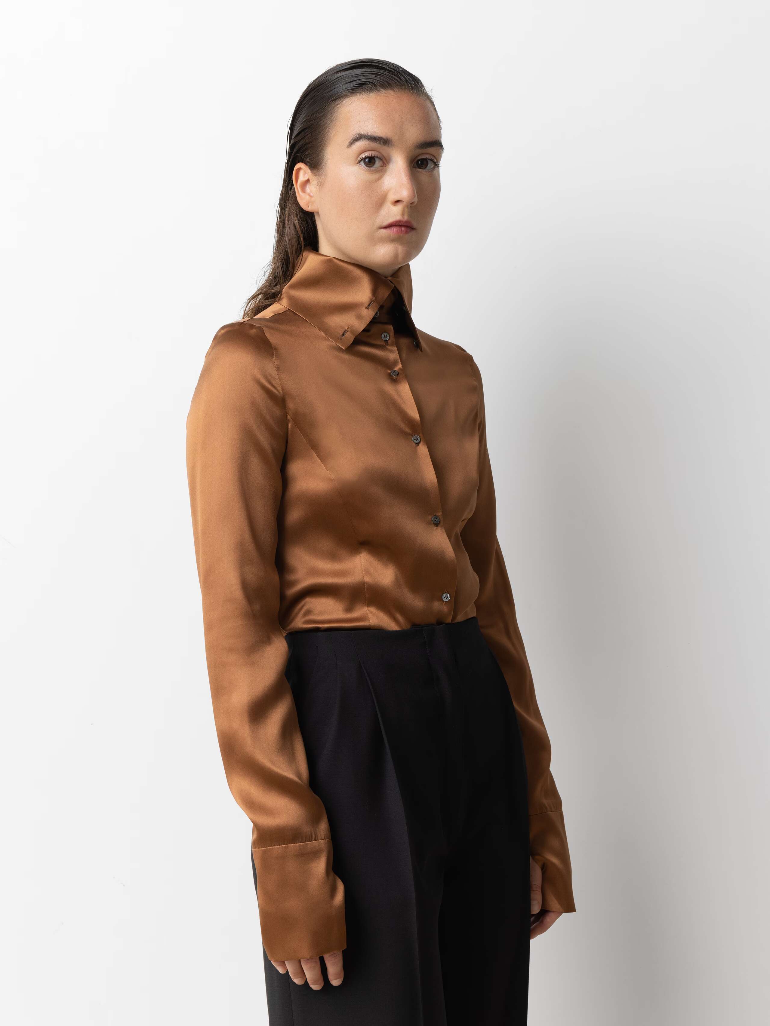 Picture of a female model wearing a brown satin silk blouse