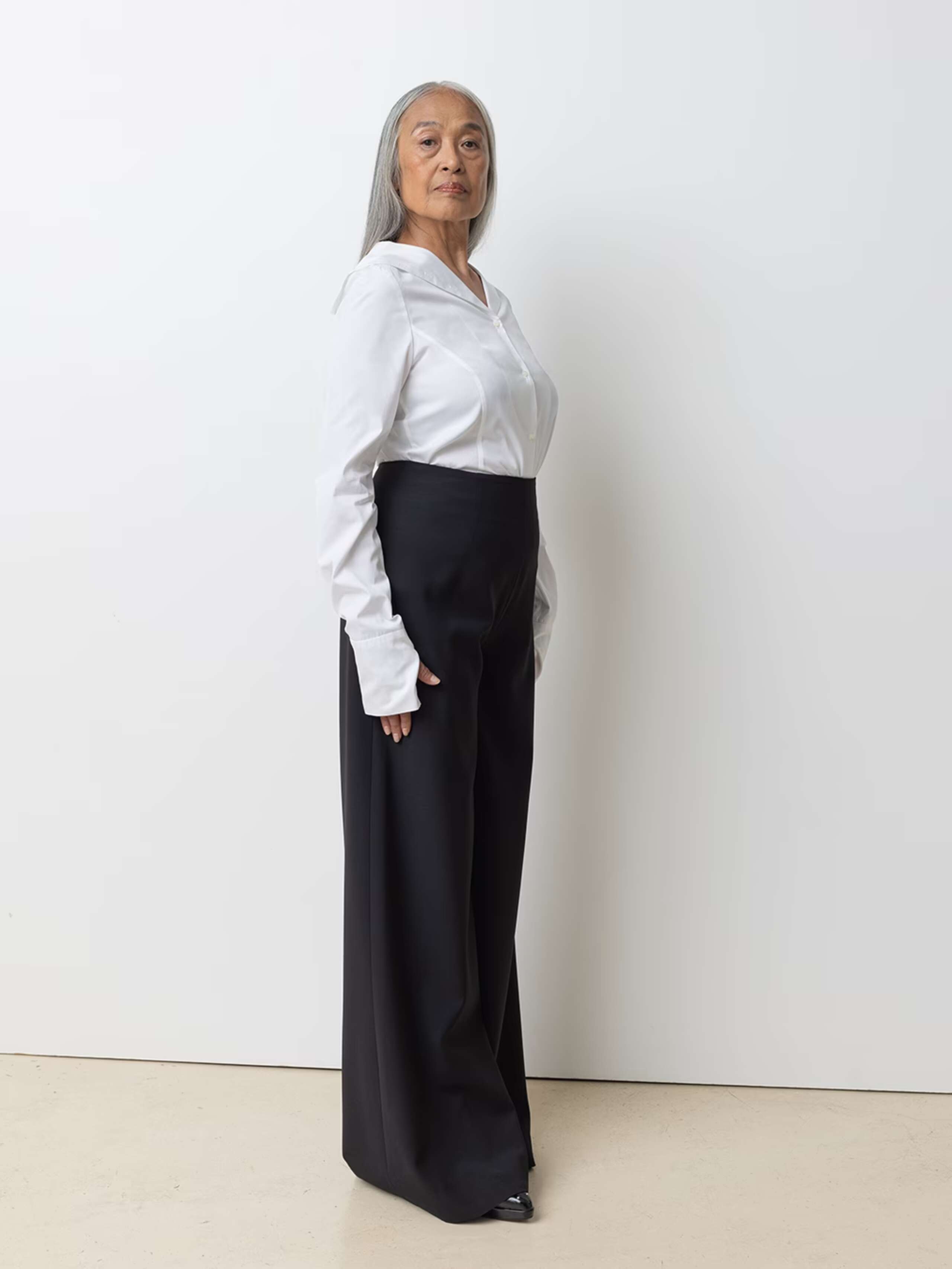 Picture of a female model wearing a whit cotton short in combination with black wool trousers