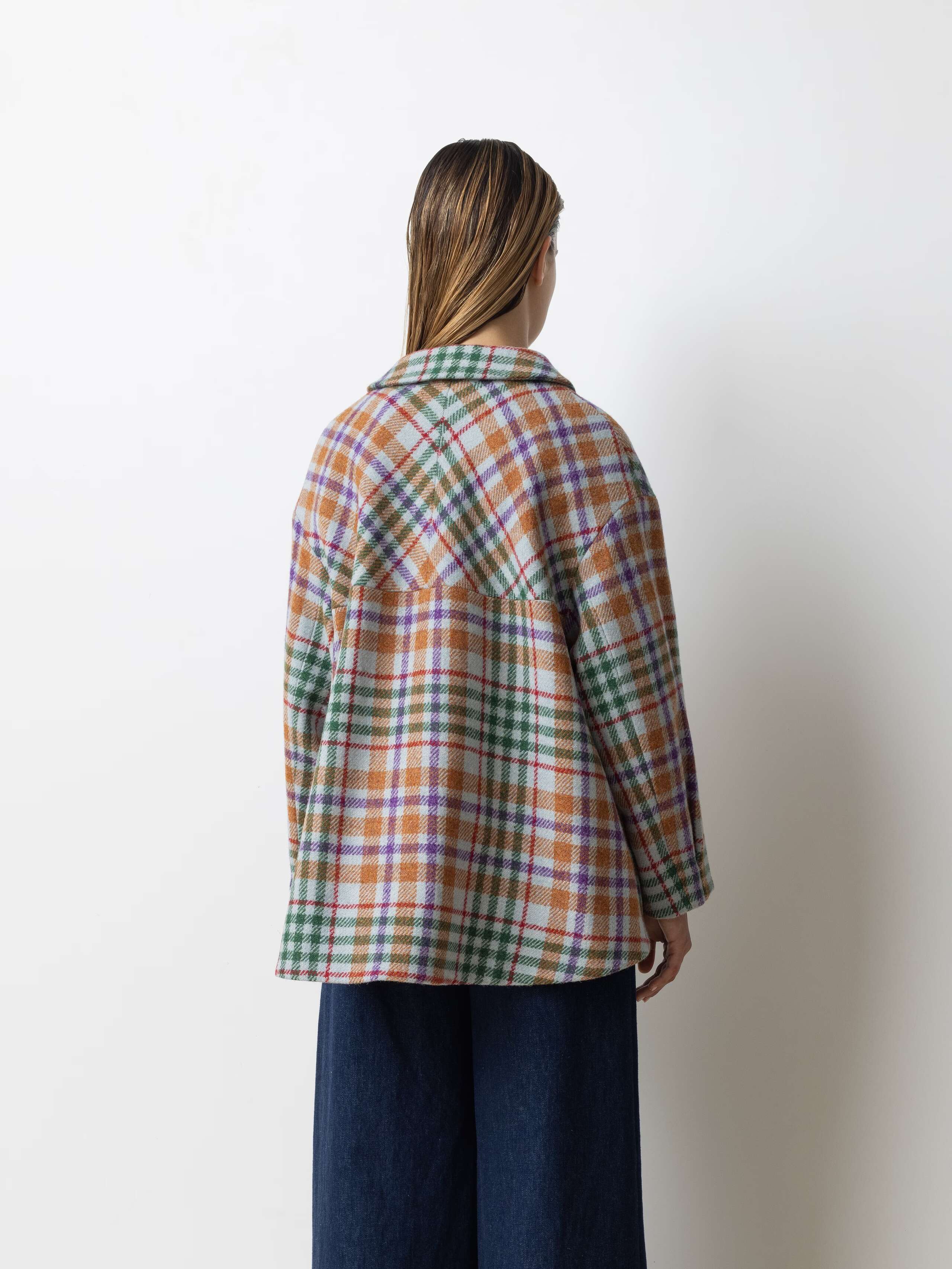 Picture of a female model wearing a wide colourful wool jacket in combination with a wide leg jeans