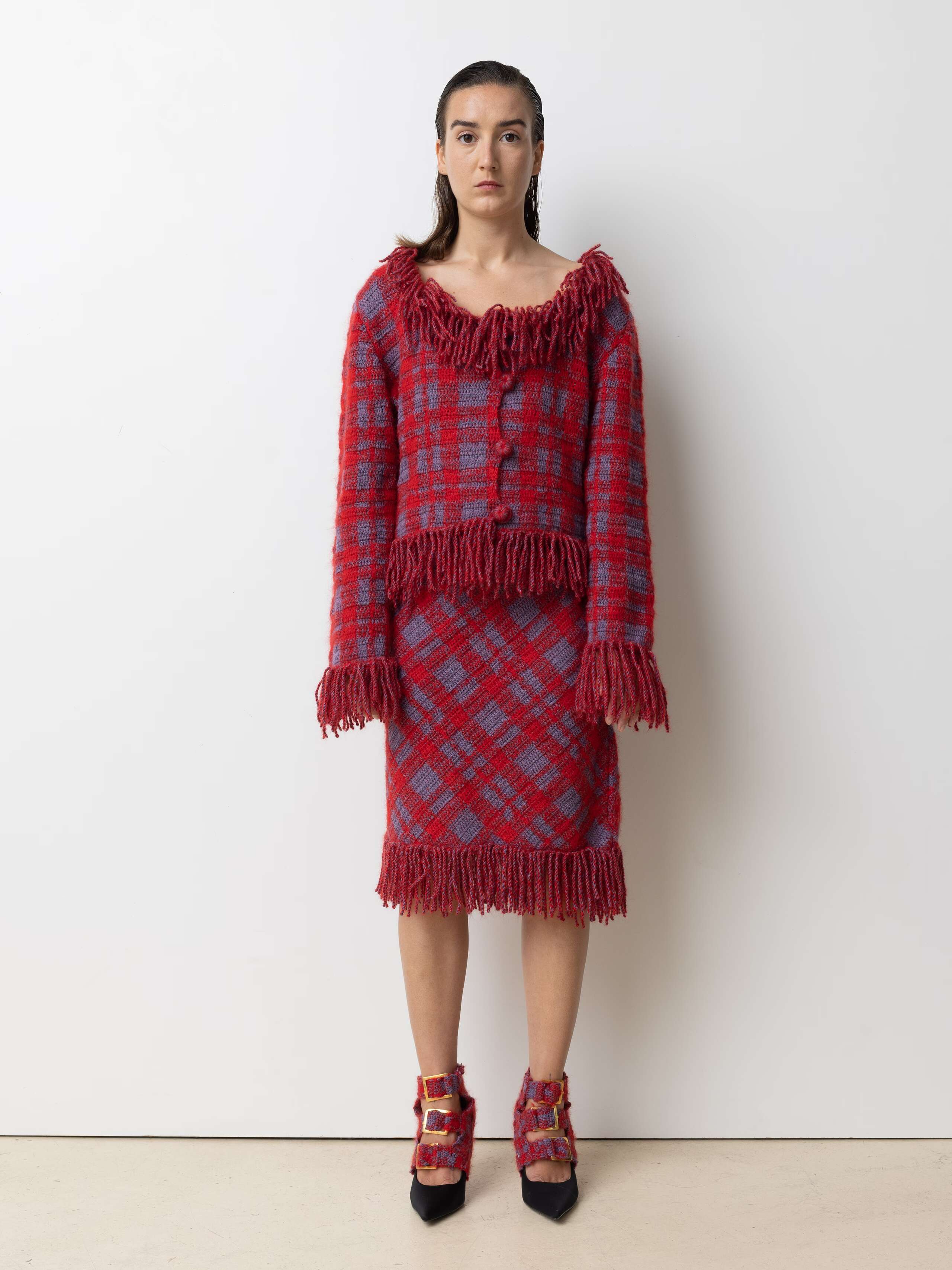 Picture of a female model wearing a red wool cardigan with a matching wool skirt