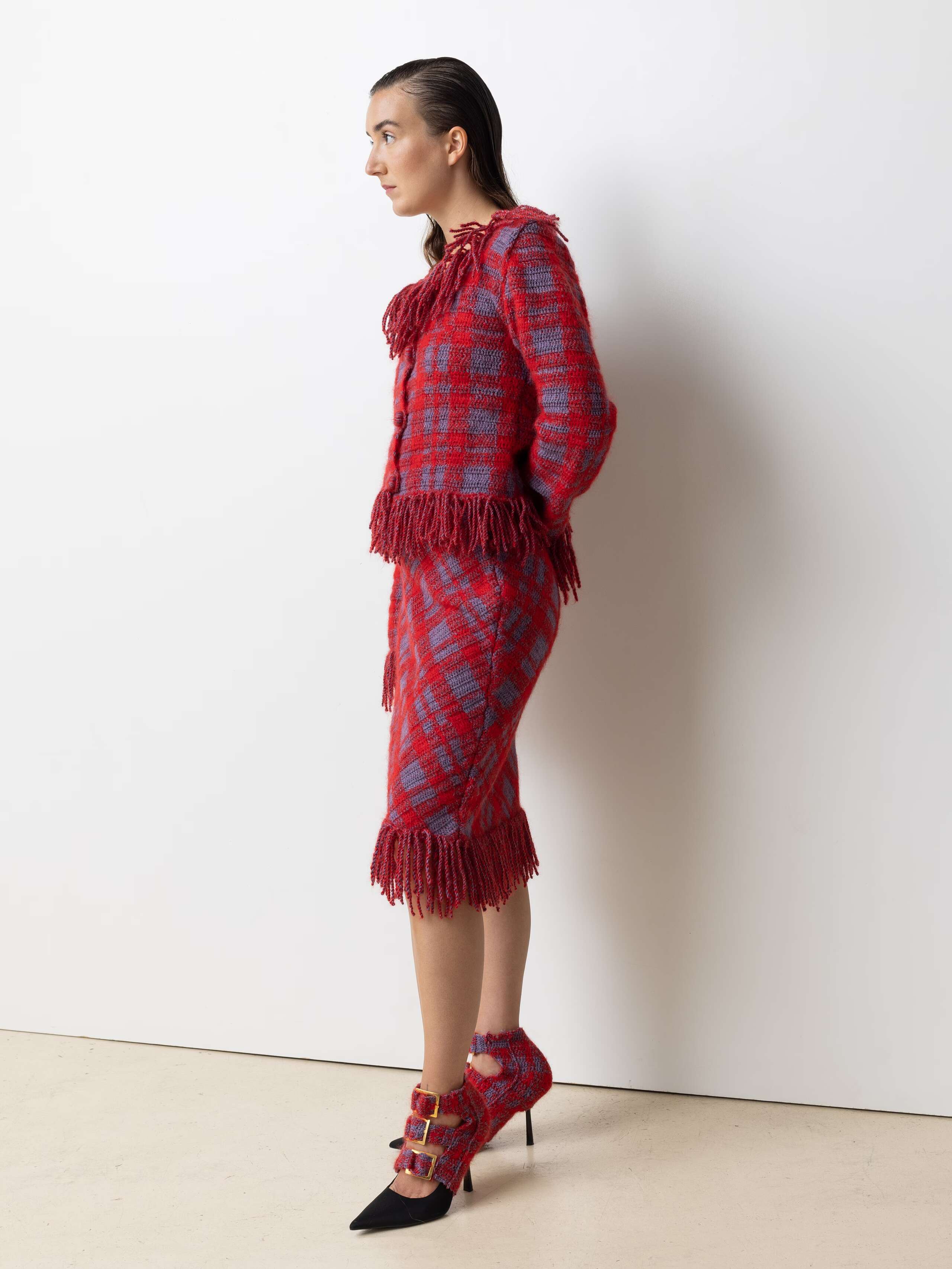 Picture of a female model wearing a red wool cardigan with a matching wool skirt