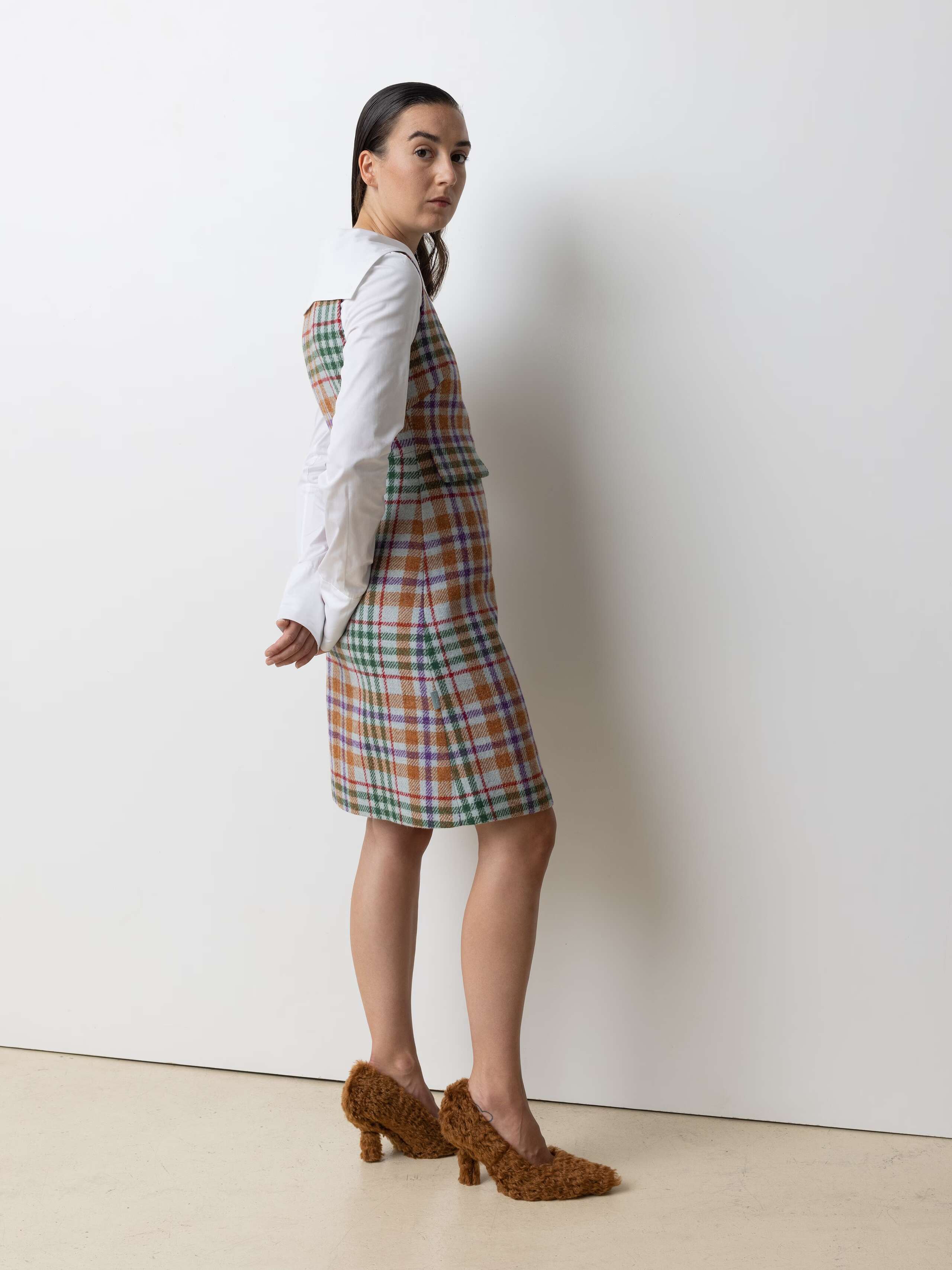Picture of a model wearing a white cotton blouse and a short Harris Tweed dress