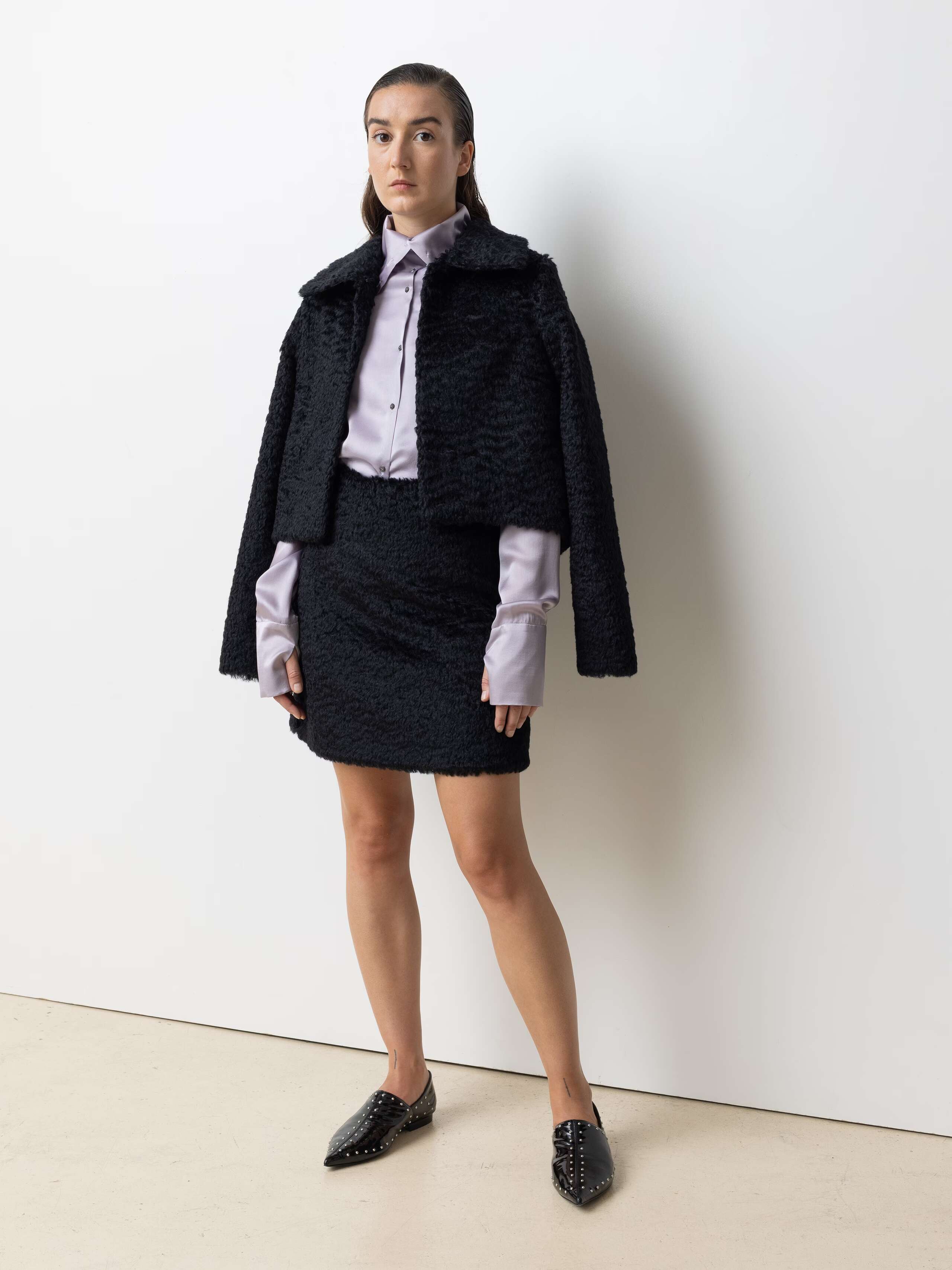Picture of a female model wearing a combination of a black mohair wool jacket and a short skirt