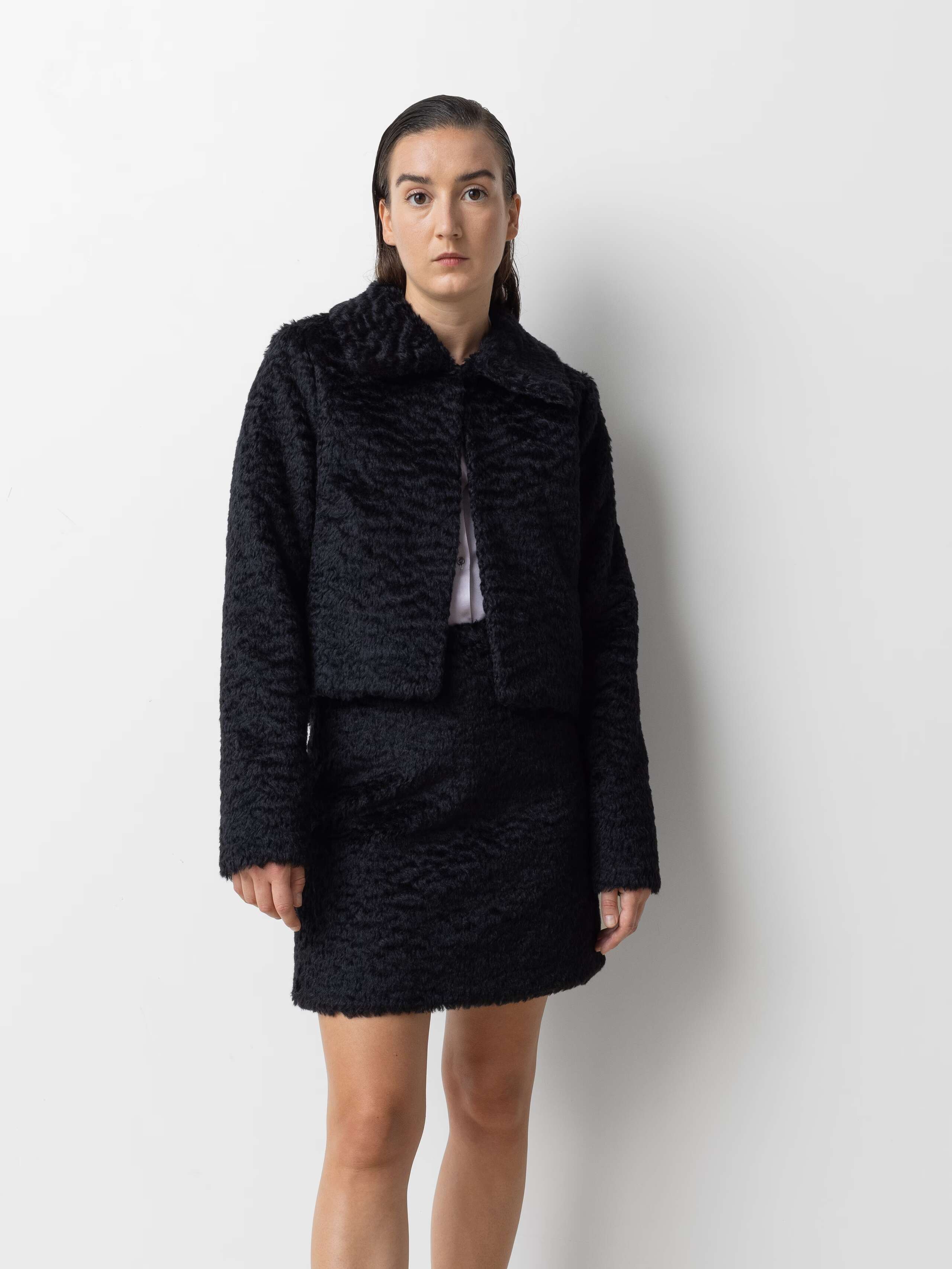 Picture of a female model wearing a combination of a black mohair wool jacket and a short skirt